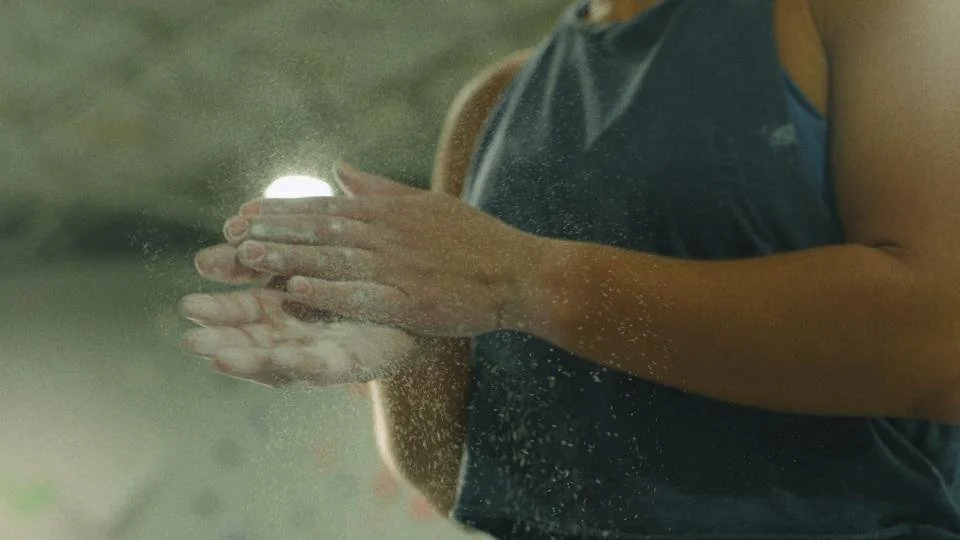 A person clapping their hands together with sand falling off them outdoors.