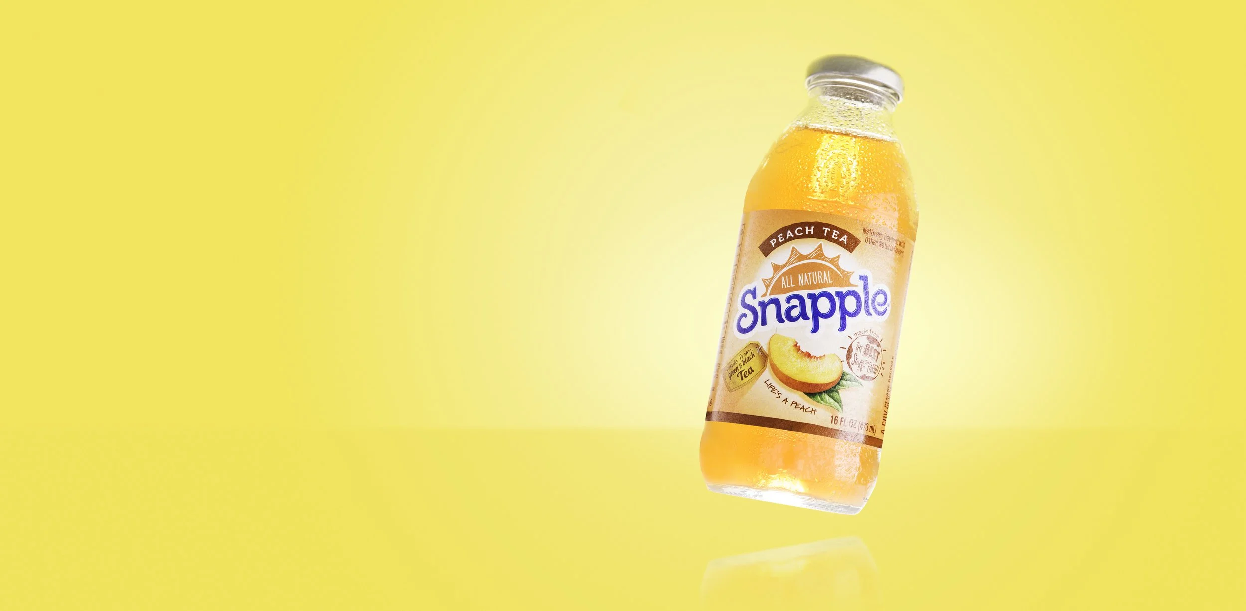 A bottle of Snapple Peach Tea with a yellow background.