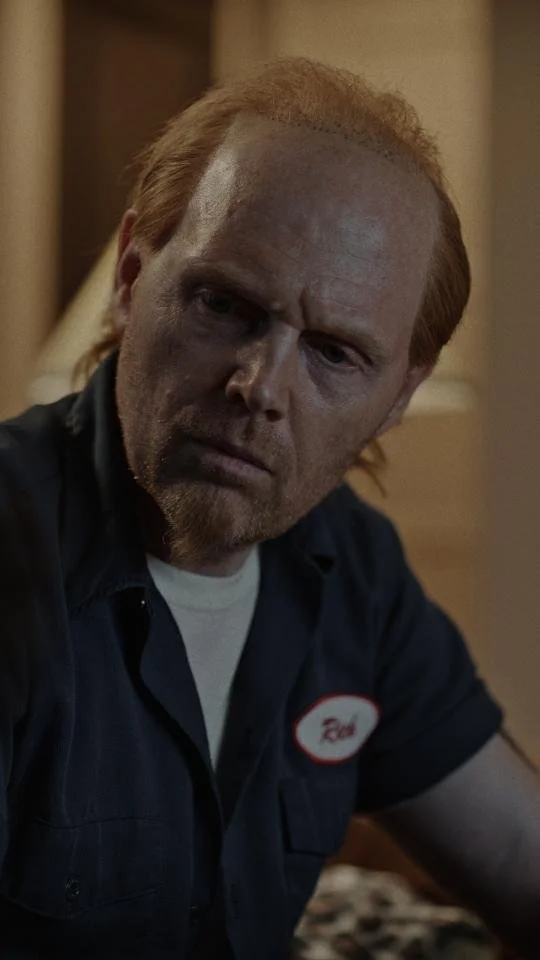 A man with red hair and a goatee wearing a dark uniform with a name tag that reads 'Ron'.
