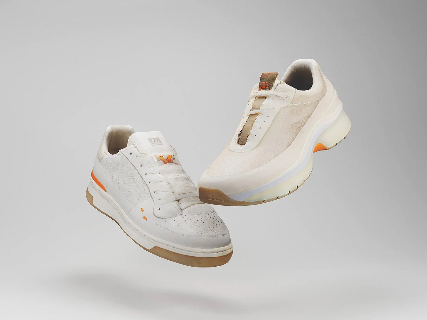 Two white sneakers with orange accents, floating against a plain background.