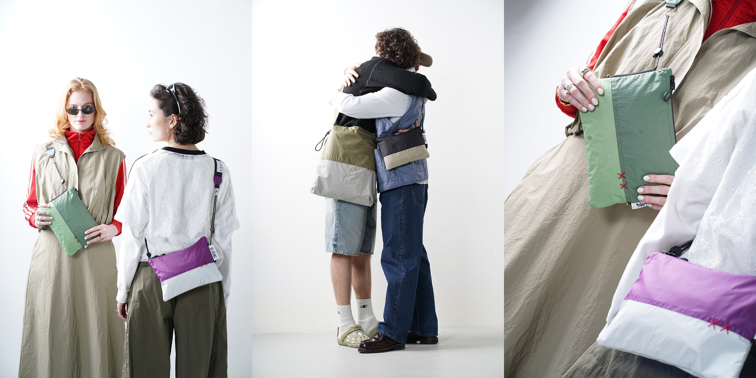Two women hugging, one wearing a black sweater and jeans, the other in a blue jacket and shorts, both holding bags. One woman with black hair, the other with curly hair. Two women standing and hugging against a white background.