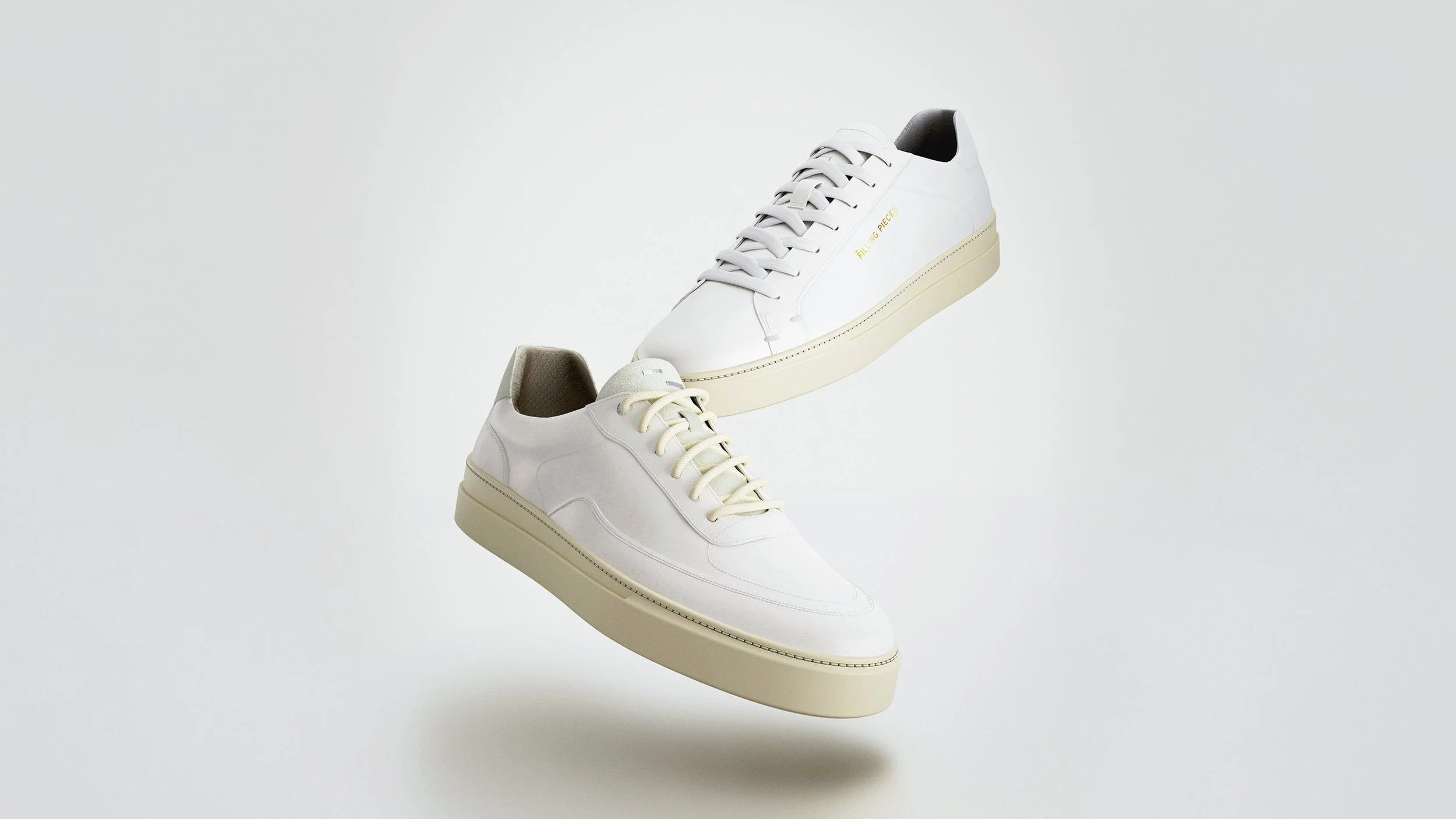 A pair of white sneakers with beige soles, floating against a white background.