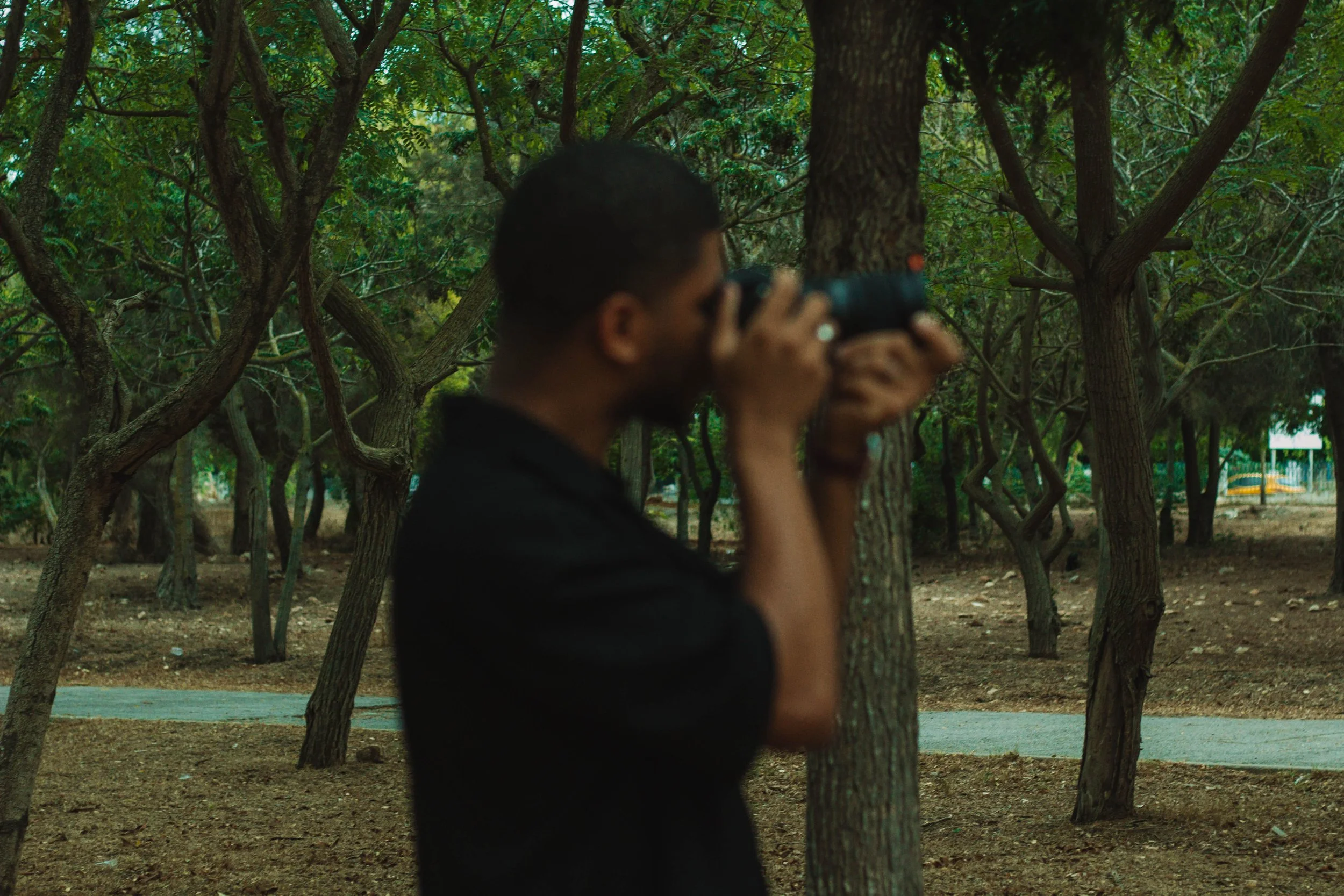 Un homme prenant des photos dans une forêt avec un appareil photo.