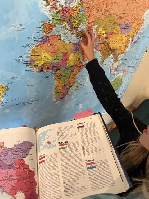 elementary montessori homeschooler using a map