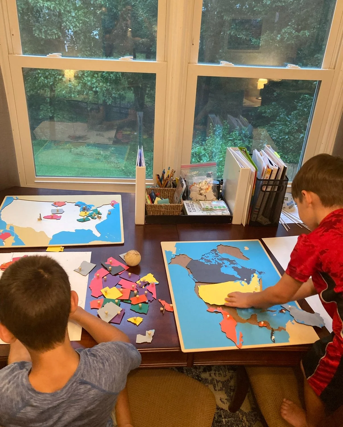 homeschool children work with Montessori puzzle maps in Geography lesson