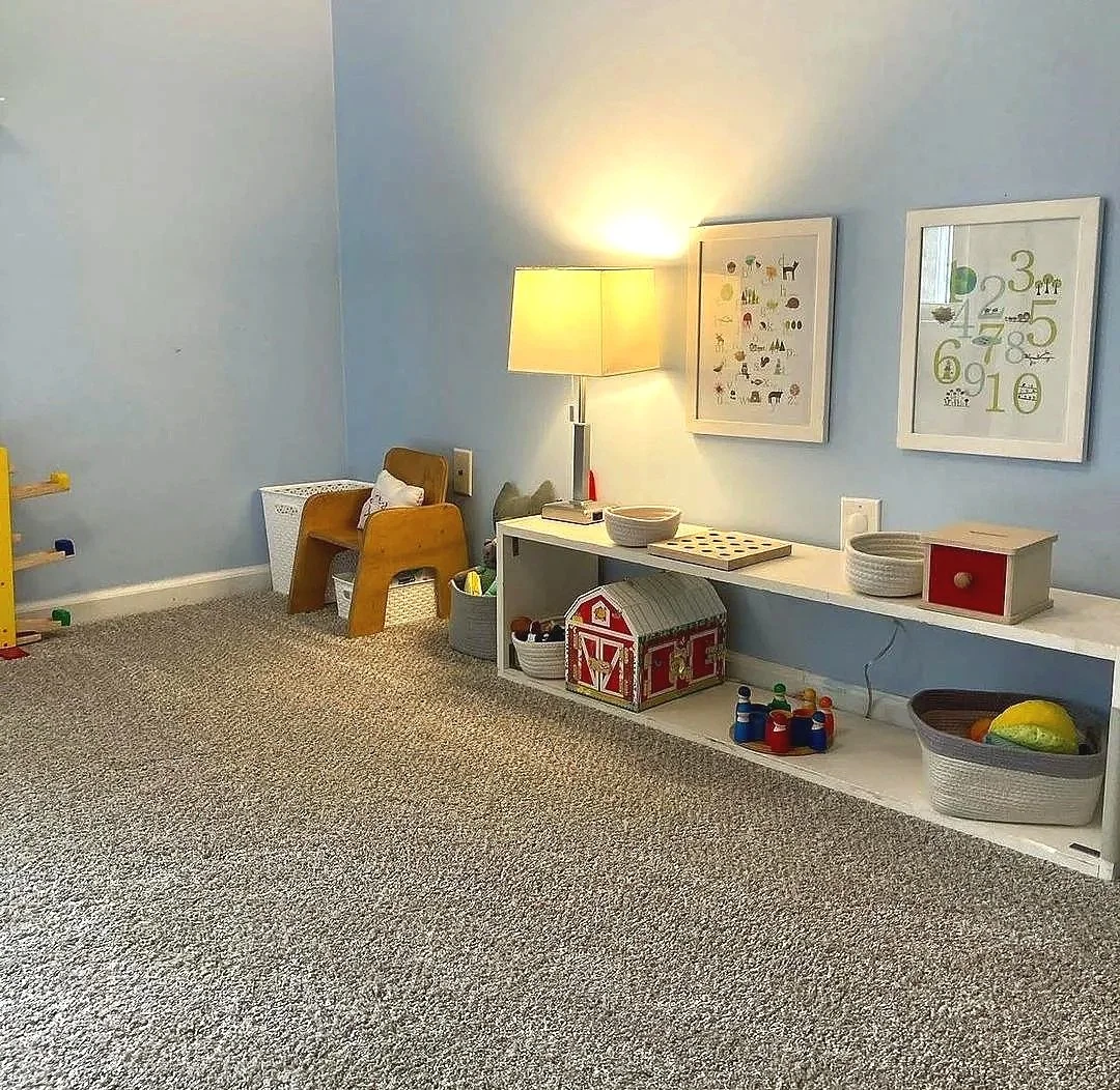 Montessori toddler shelves prepared in a home with toddler activities and low art