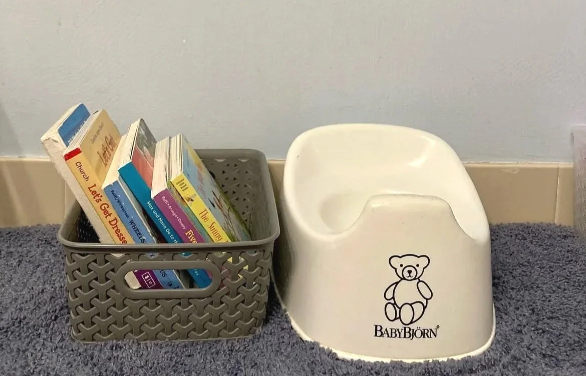Montessori toddler bathroom area with a basket of books and toilet