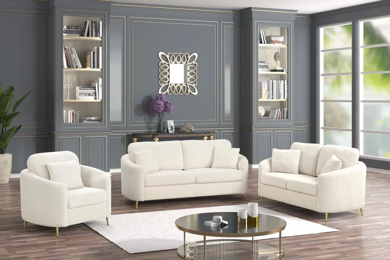 Living room with blue paneled walls, cream sofas, a round coffee table, built-in bookshelves, large windows, and a decorative mirror with a vase of purple flowers.
