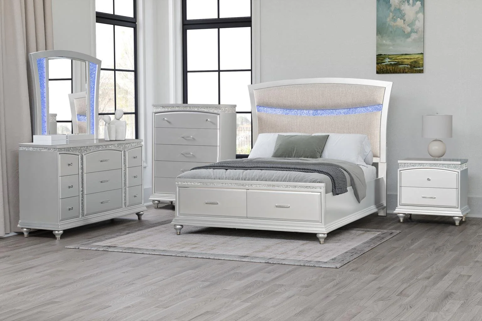 A modern, elegant bedroom with a white bed, matching white nightstand and dresser, large windows, gray and white decor, and a small landscape painting on the wall.
