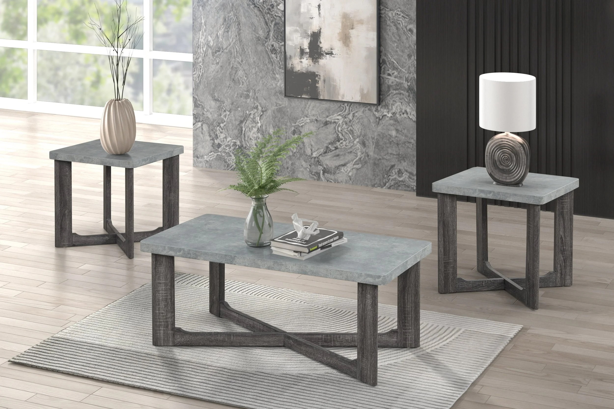 Modern living room with a gray and black color scheme, featuring stone-textured tables, a vase with fern, a table lamp with a white shade, and abstract artwork on a marbled wall.