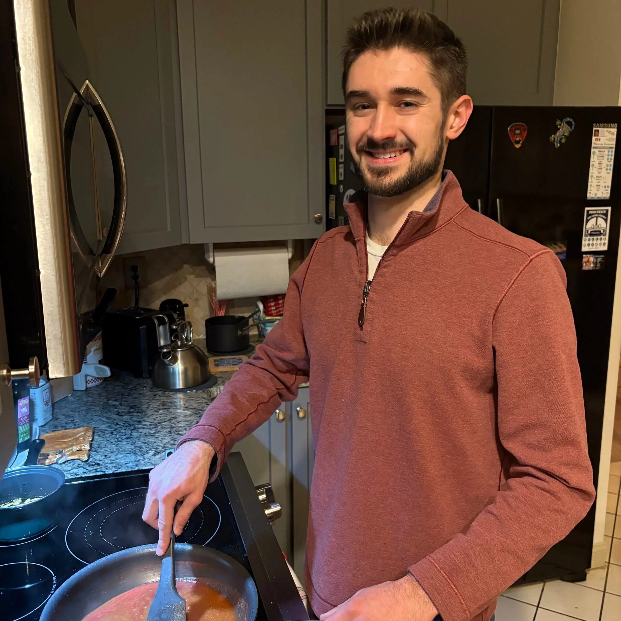 A man smiling while cooking in a kitchen.