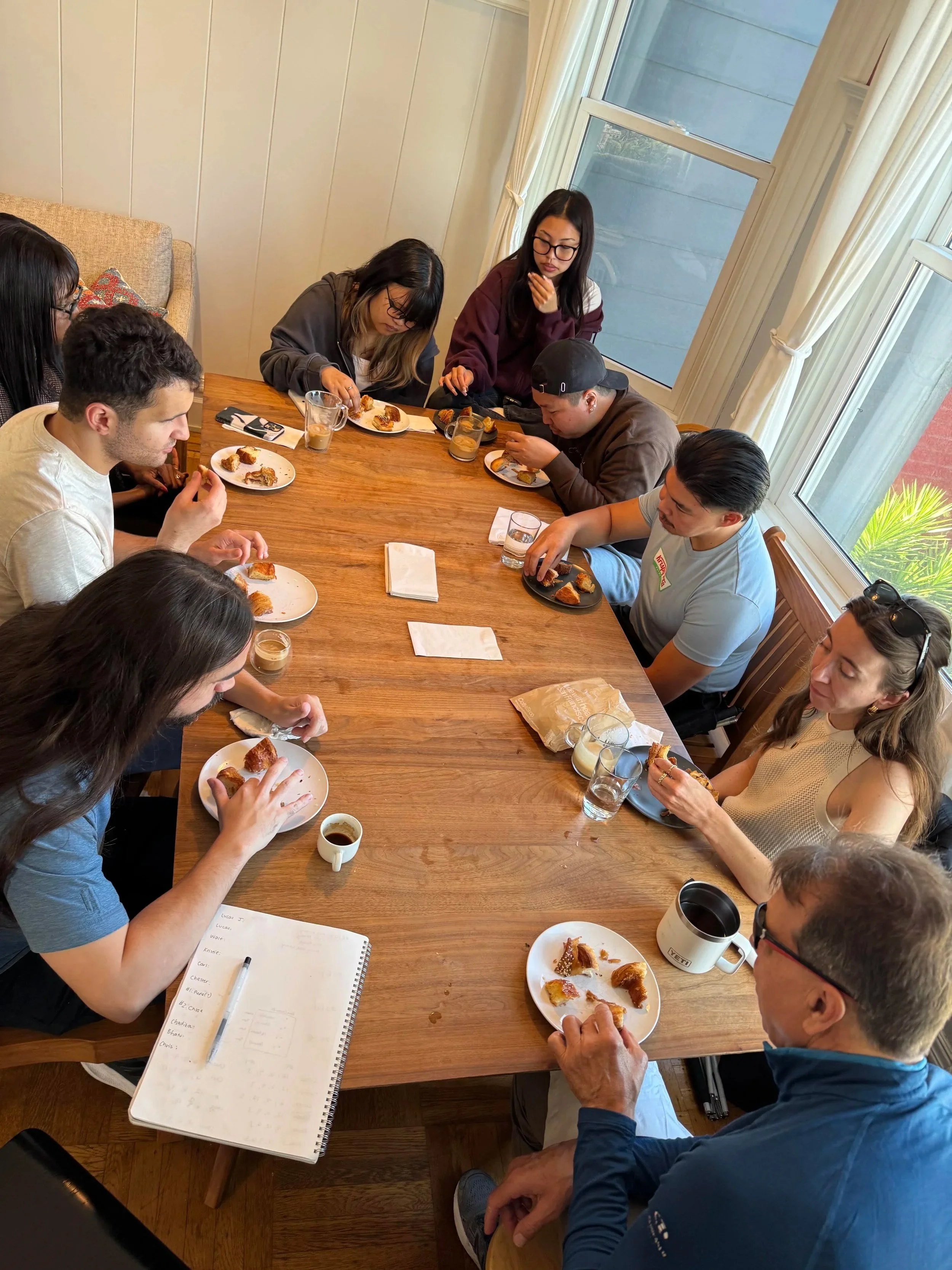 Several people eat pastries around a table