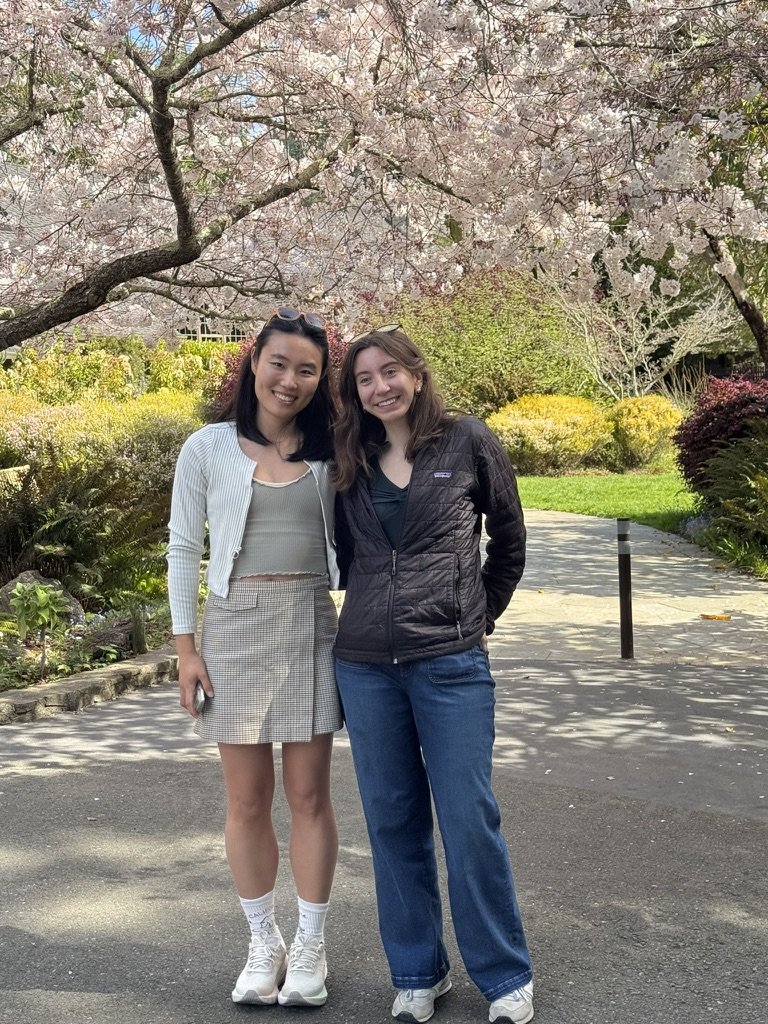 Kristie and Jungyeon pose in front of full-bloom cherry blossom trees.