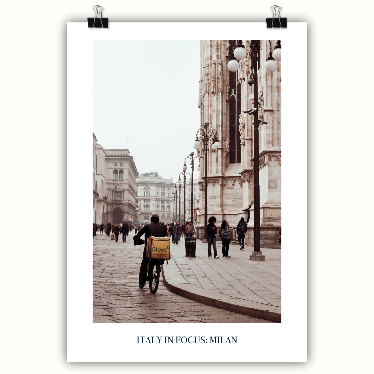 A poster featuring a delivery cyclist riding alongside the magnificent Duomo on a grey day in Milan.