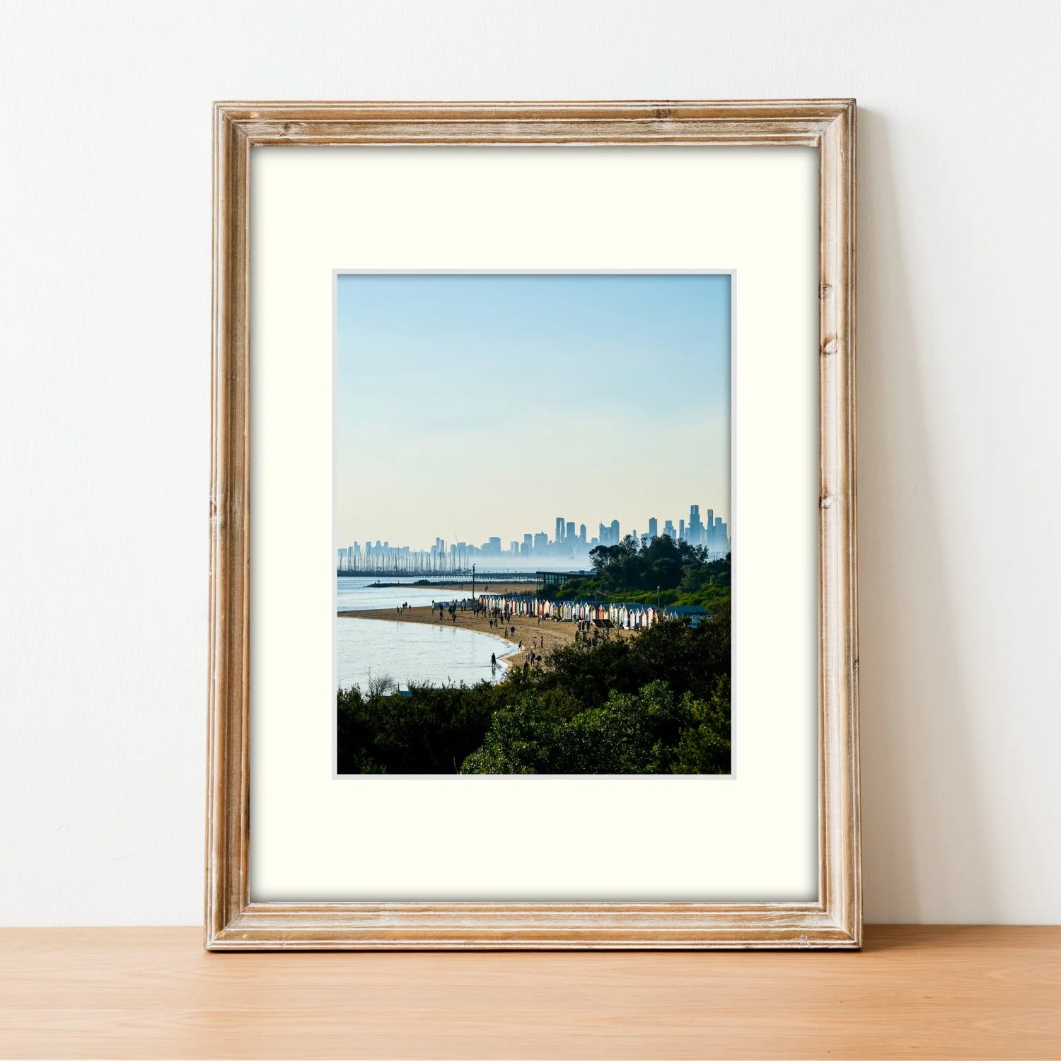 Bayside Horizon print and mount styled in a light-wood frame, sitting on a modern sideboard.