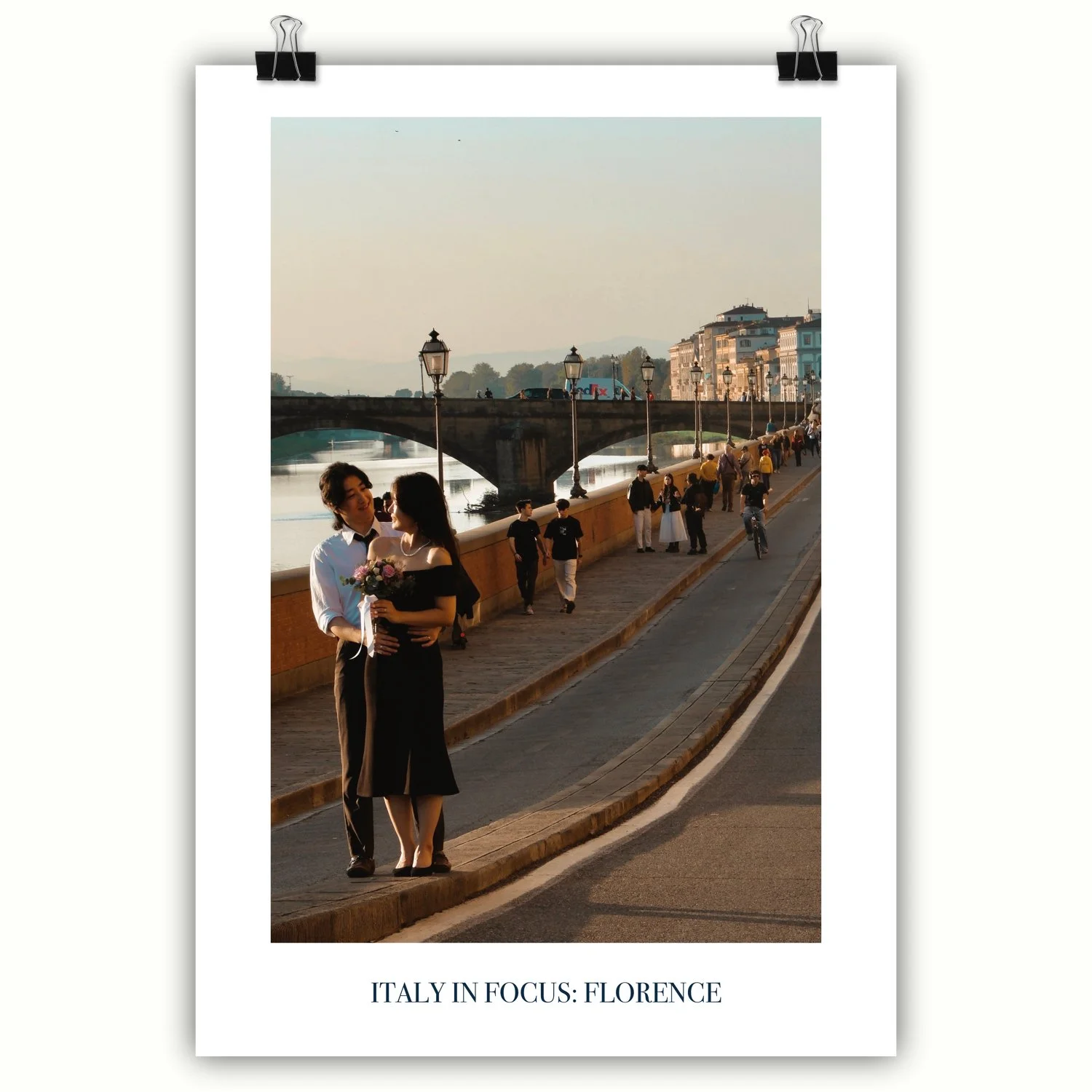 A poster featuring a couple embracing on a riverside walkway in Florence, with an historic bridge and lamp posts in the distance.