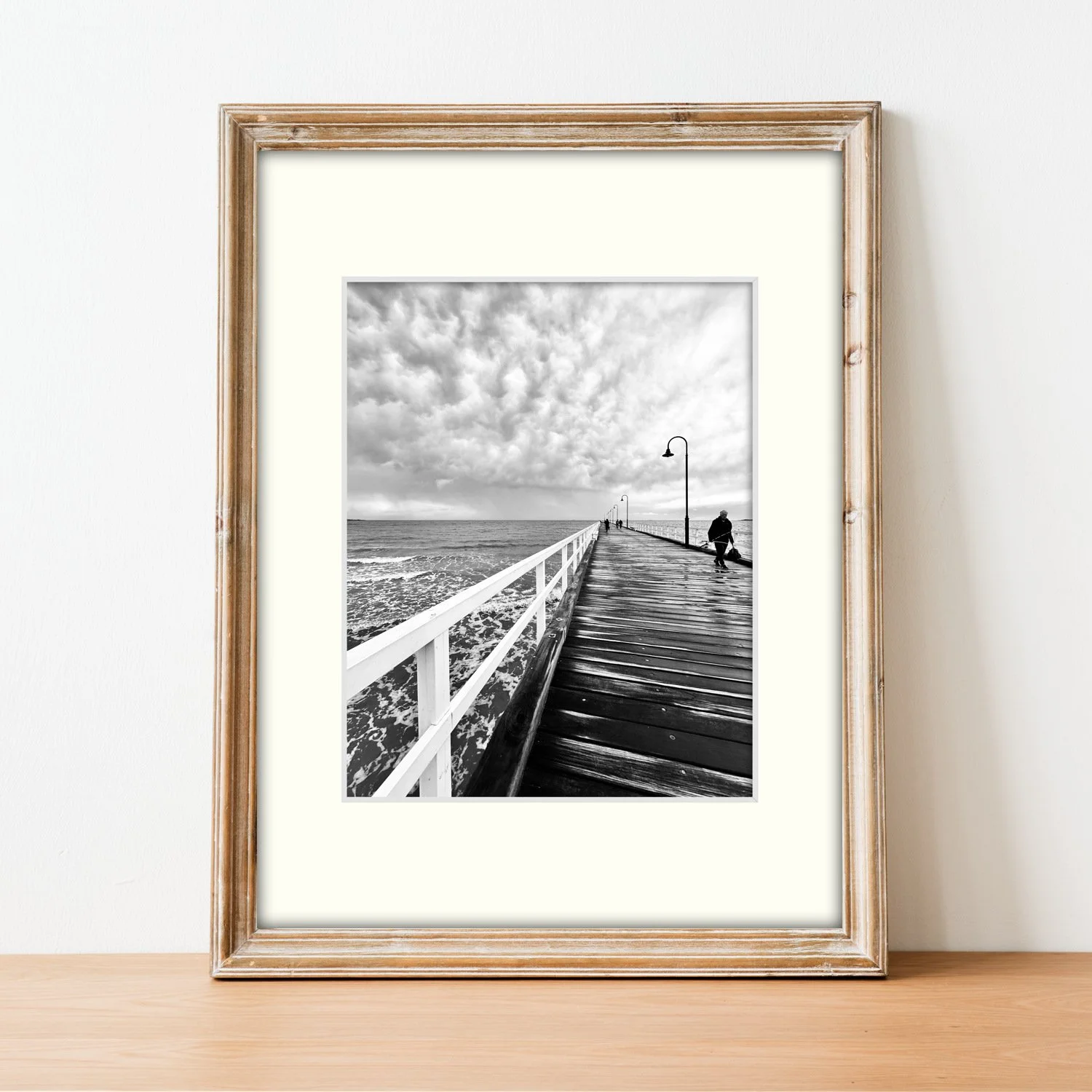 Frame mount with B&W print of The Lone Fisherman in finalised picture frame sitting on sideboard.