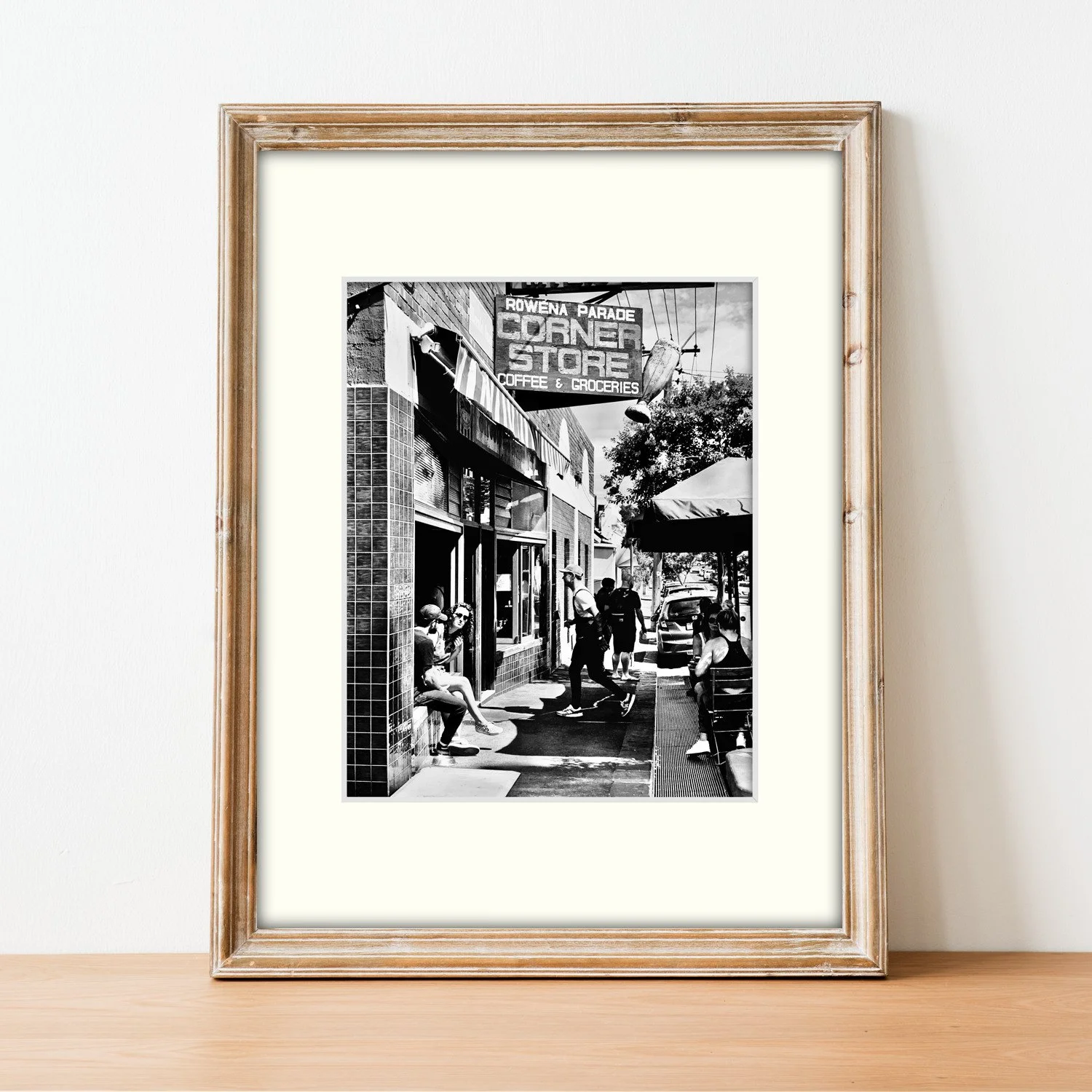 A monochrome print of a Richmond milk bar styled in a slim timber frame, sitting on a sideboard.
