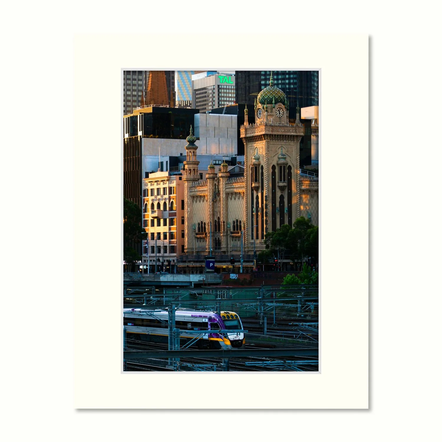 A frame mount with print of the Forum Facade in golden light with a purple V/Line train passing through the rail yards in the foreground.