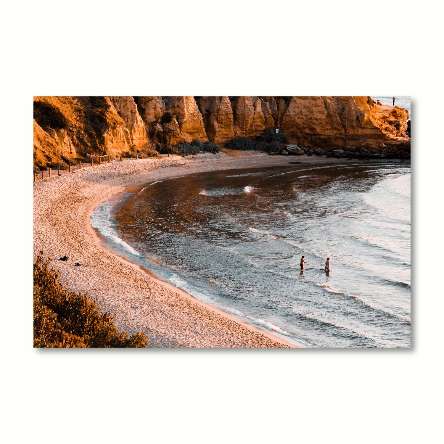 Fine art print of rich orange sandstone cliffs surrounding a peaceful bay, with rolling waves.