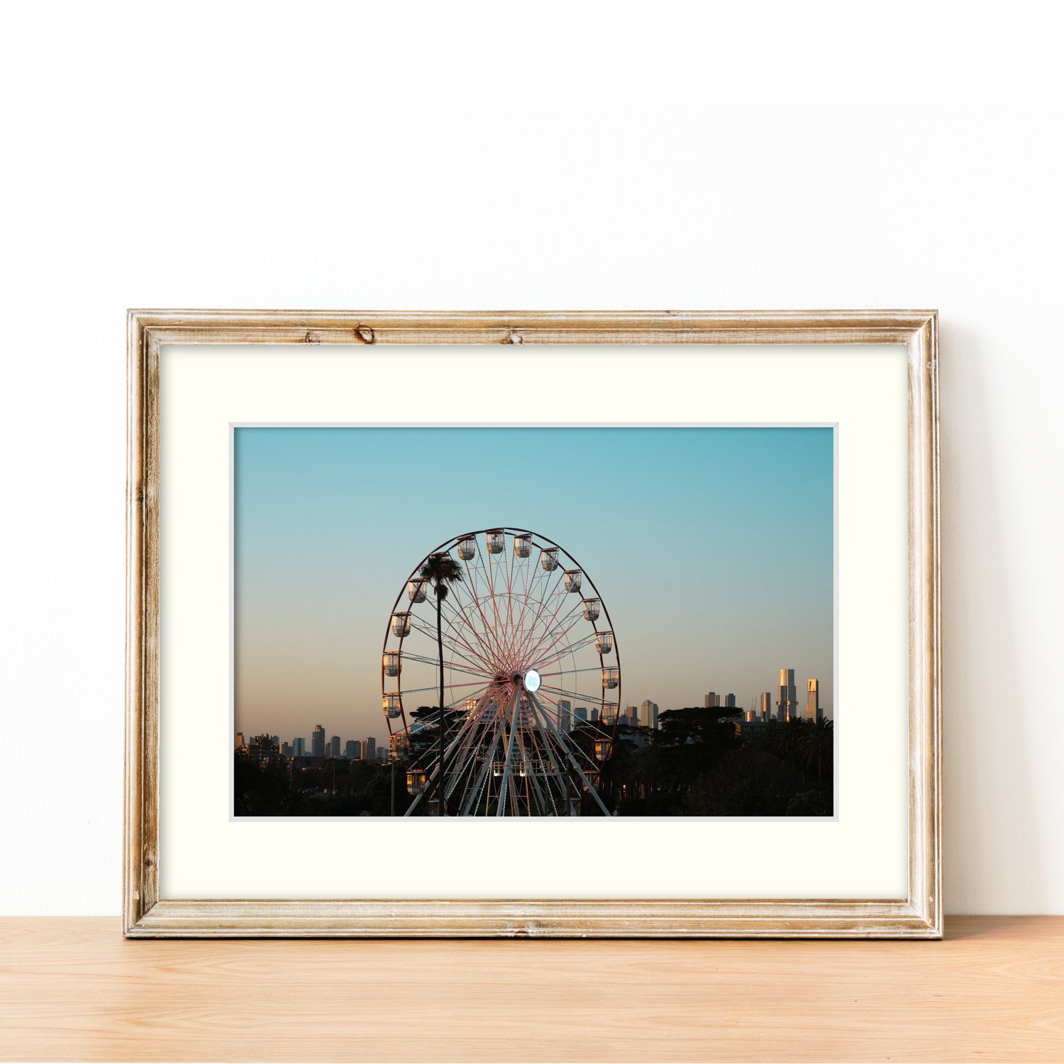 The Summer Wheel print and mat board framed in modern oak and sitting on a sideboard.