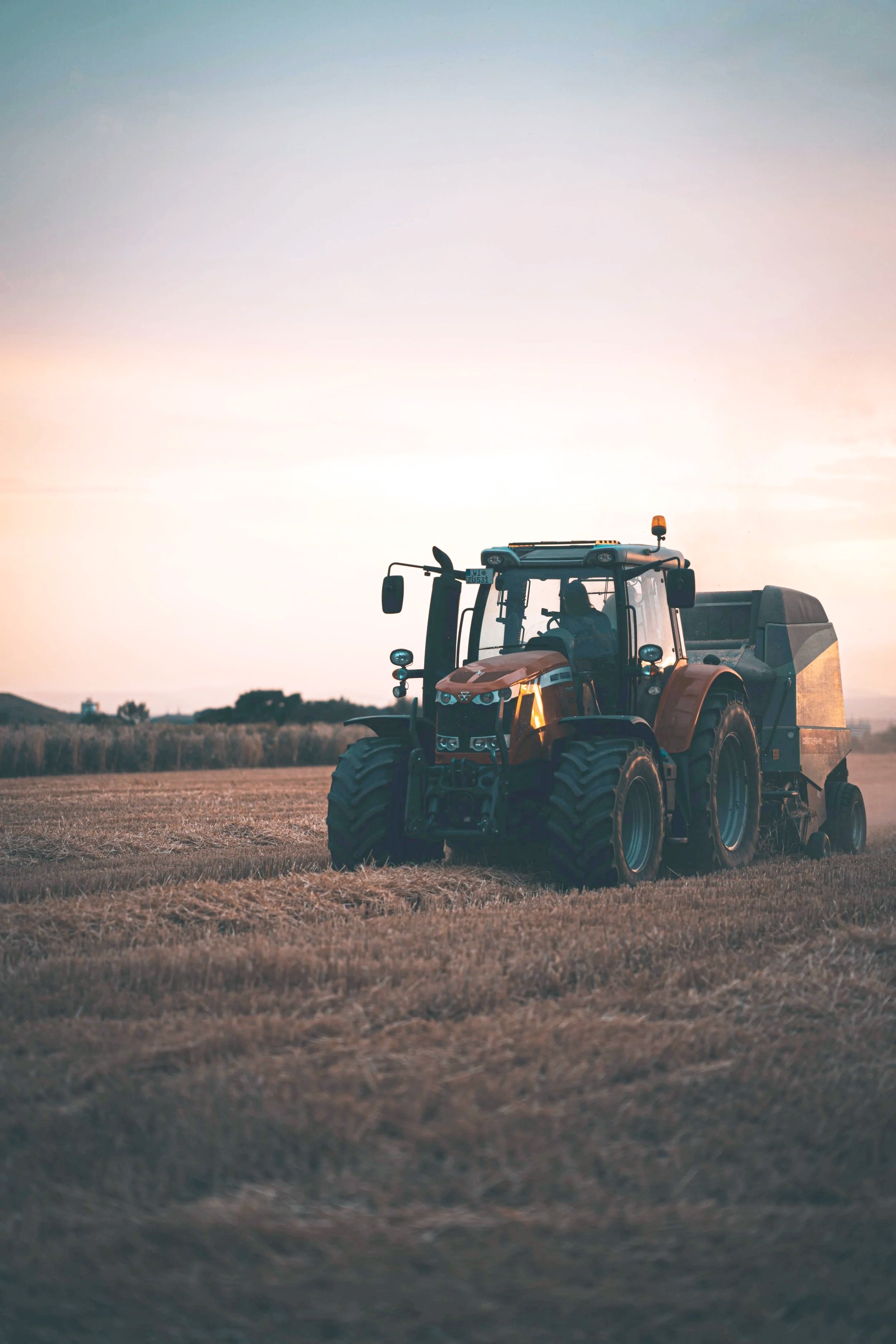 Tractor working on a farm during sunset.