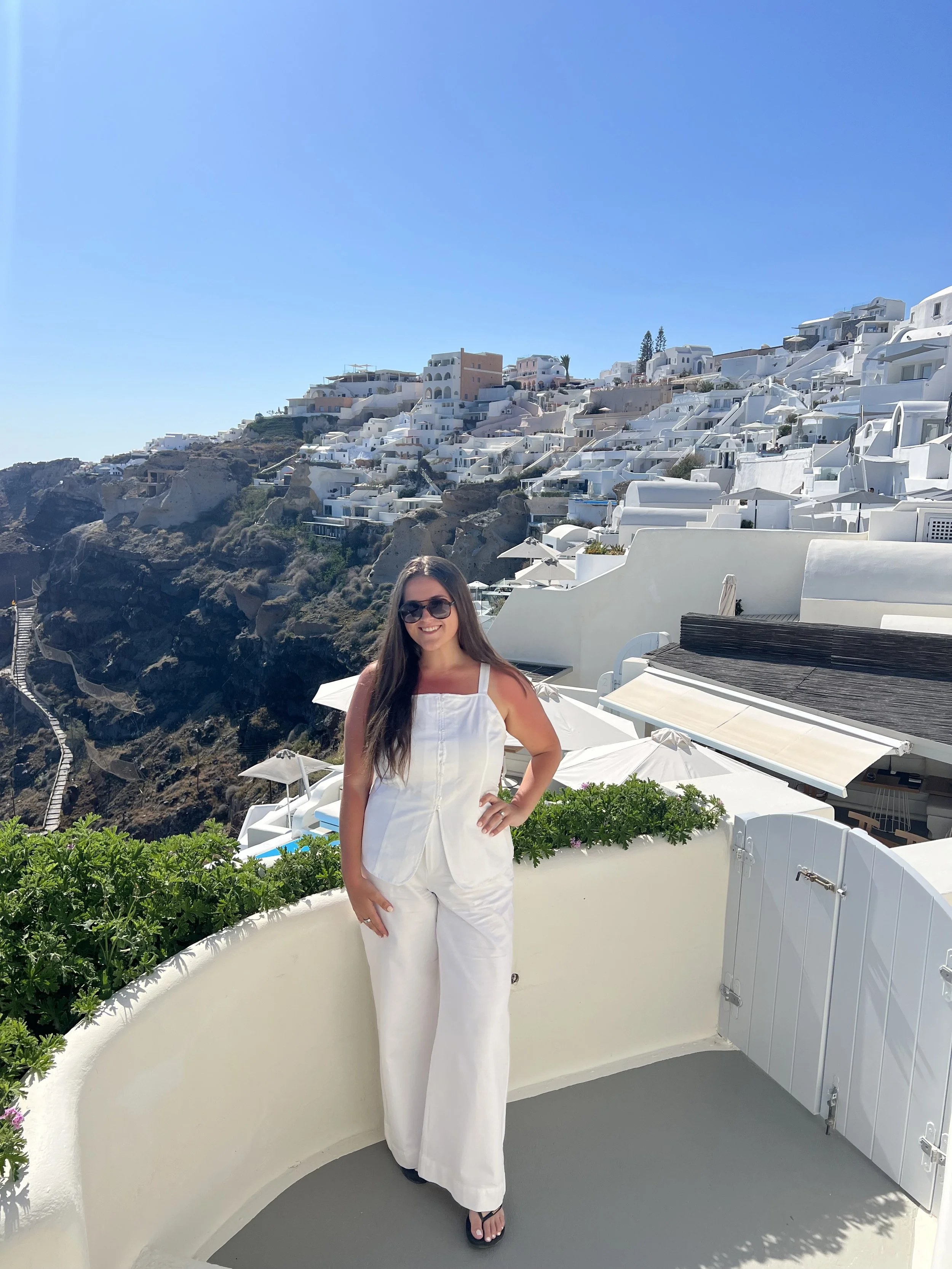 Luxury travel advisor Angela on a terrace overlooking a panoramic view of Santorini, Greece