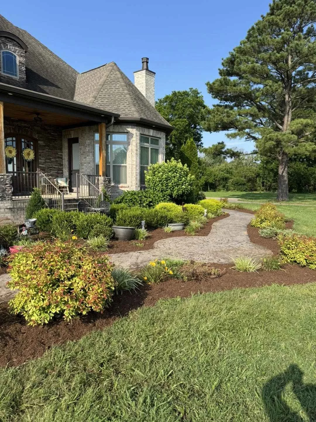 Front yard landscape design with paver walkway, shrubs, and fresh mulch beds in Middle, TN