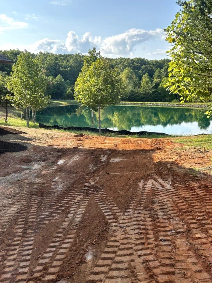 Before sod installation in McMinnville, TN — freshly graded dirt area beside a lake, prepared for new sod.