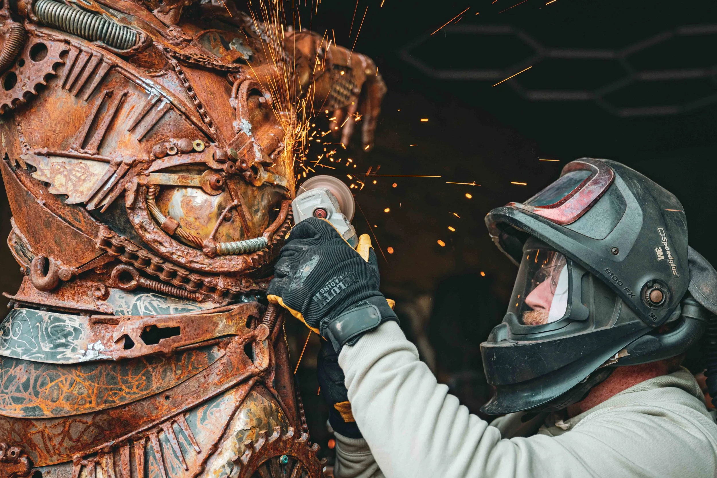 Man wearing a helmet while welding a steel sculpture