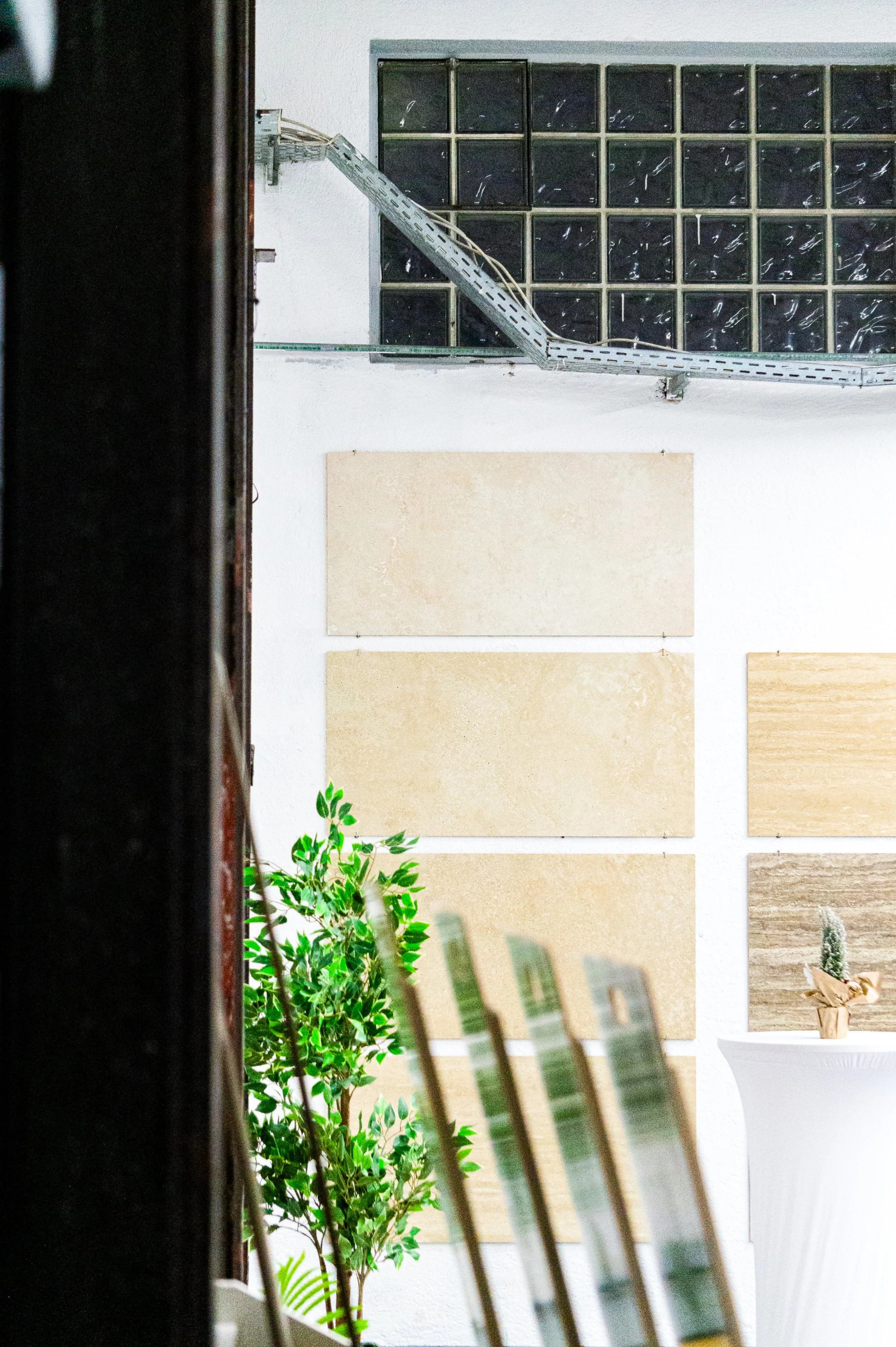 Innenansicht eines Raums mit Pflanzen, Wanddekorationen und einer Glasscheibe. Es ist ein moderner, heller Raum mit dekorativen Elementen. Aufgenommen von Hilal Studios.