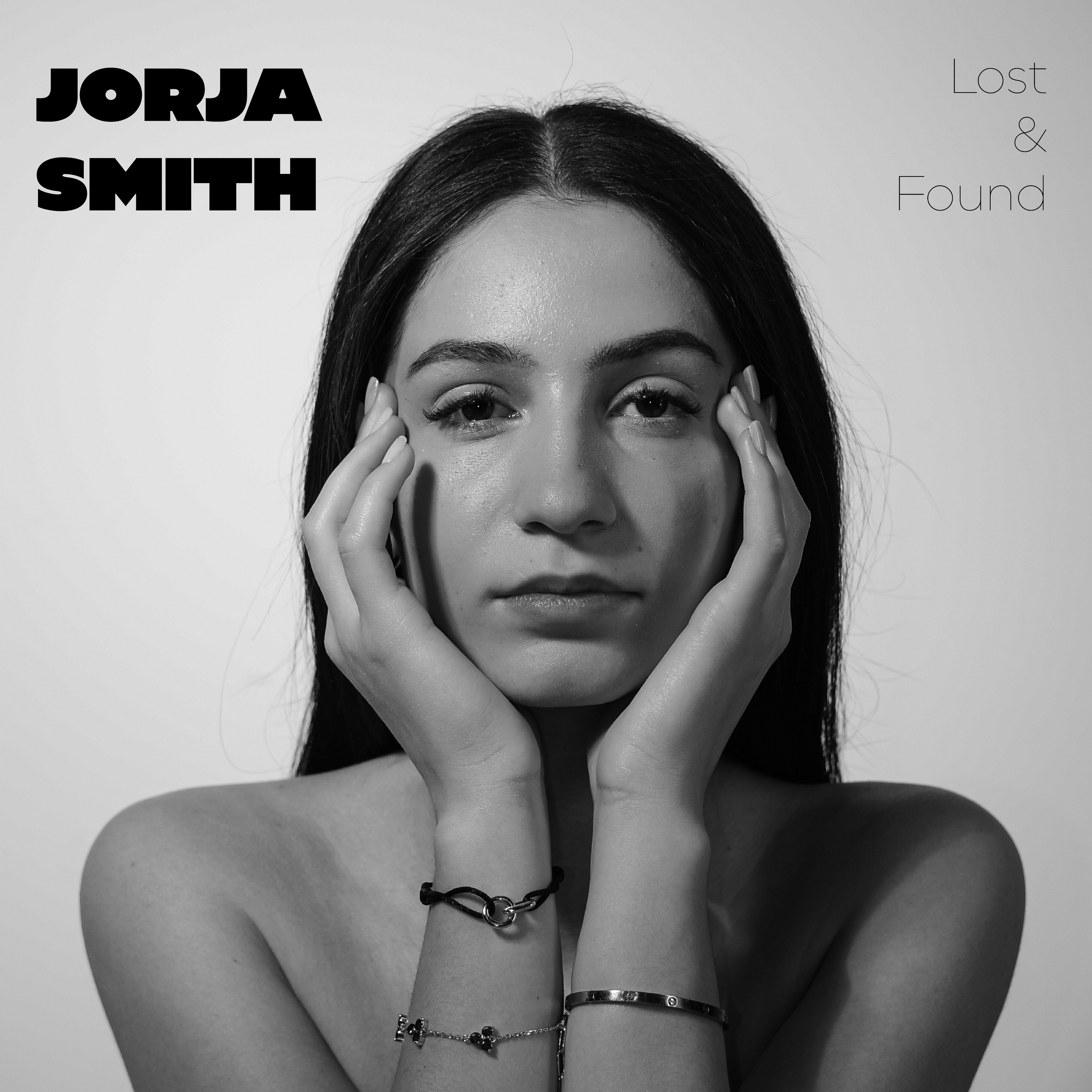 Schwarz-weiß Porträt einer jungen Frau mit dunklem Haar, die ihre Hände an den Kopf hält. Früherer Titel auf dem Bild: 'JORJA SMITH', und klein in der oberen rechten Ecke steht 'Lost & Found'. Aufgenommen und Erstellt von Hilal Studios.