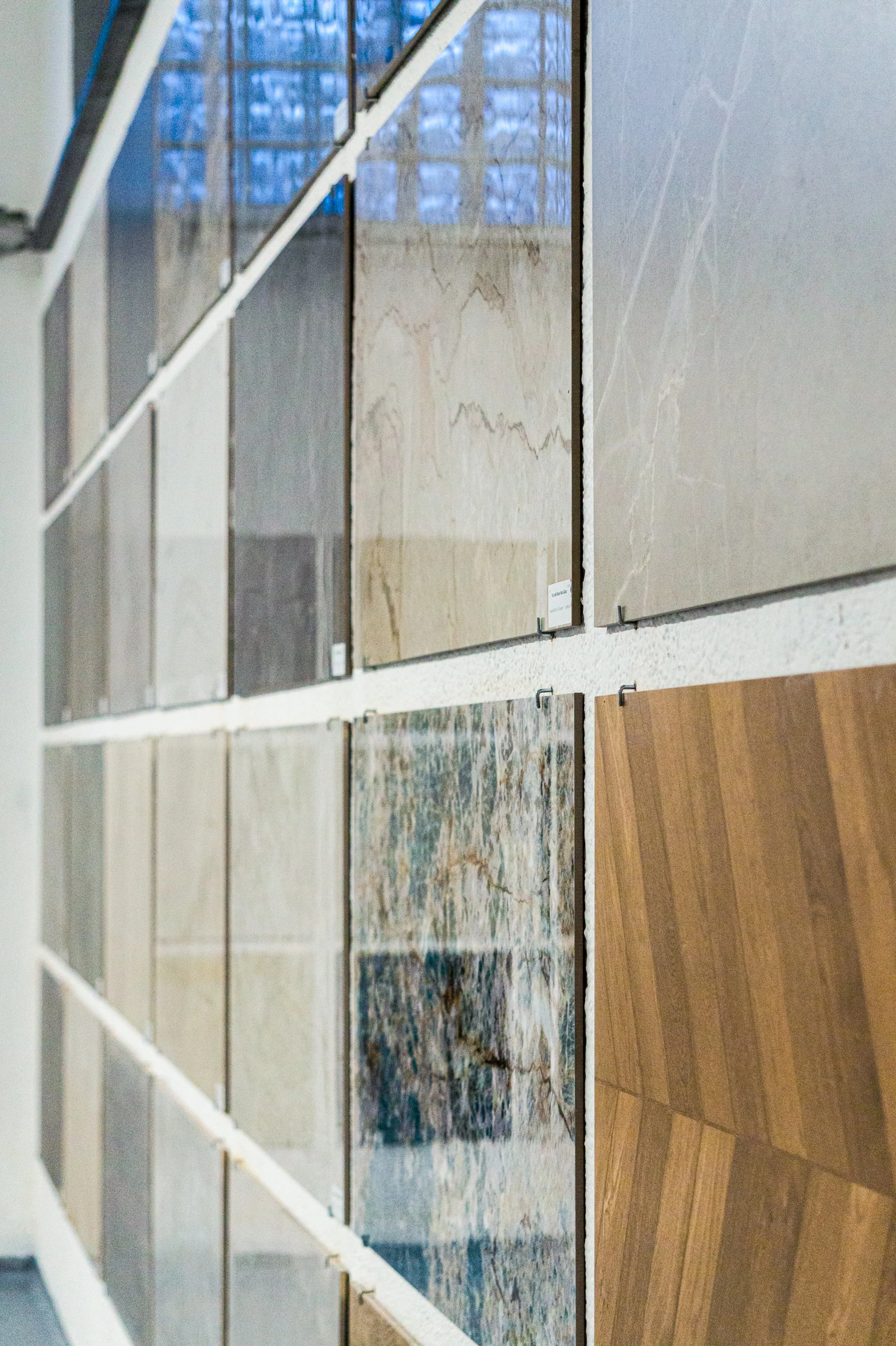 Verschiedene Fliesen- und Bodeneinlagen in einem Schaufenster, von oben nach unten sichtbar, in einem Warte- oder Verkaufsraum. Aufgenommen von Hilal Studios.