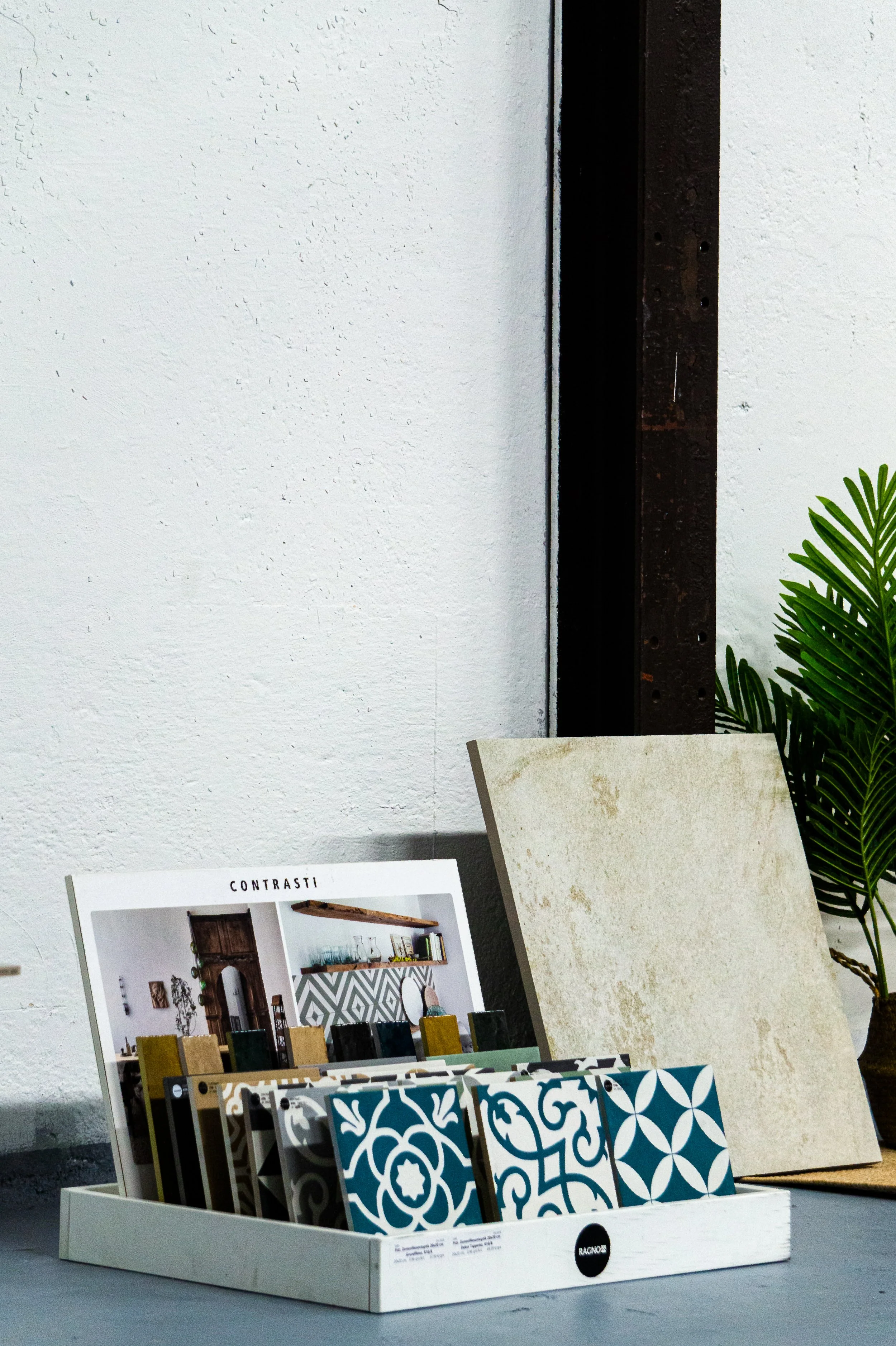 Vorlage mit Fliesenmustern, Musterkatalog und einer künstlichen Pflanze. Aufgenommen von Hilal Studios.