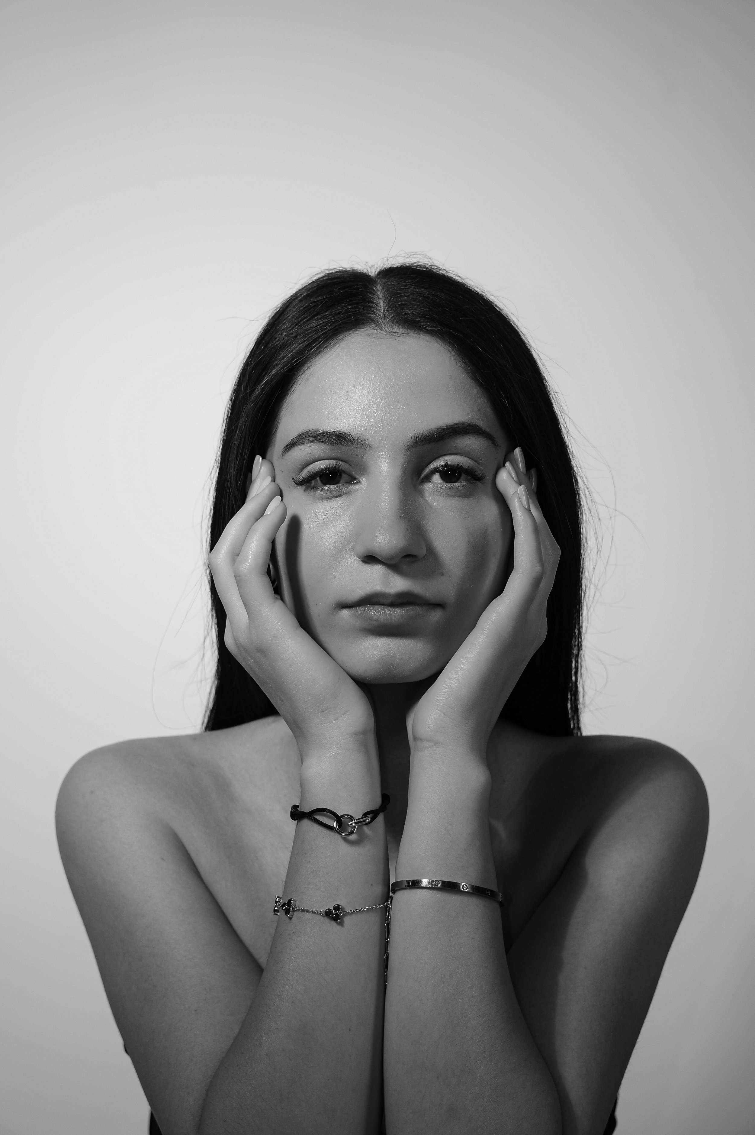 Schwarz-Weiß-Porträt einer jungen Frau mit langem dunklem Haar, die sich die Hände an das Gesicht hält. Aufgenommen von Hilal Studios.