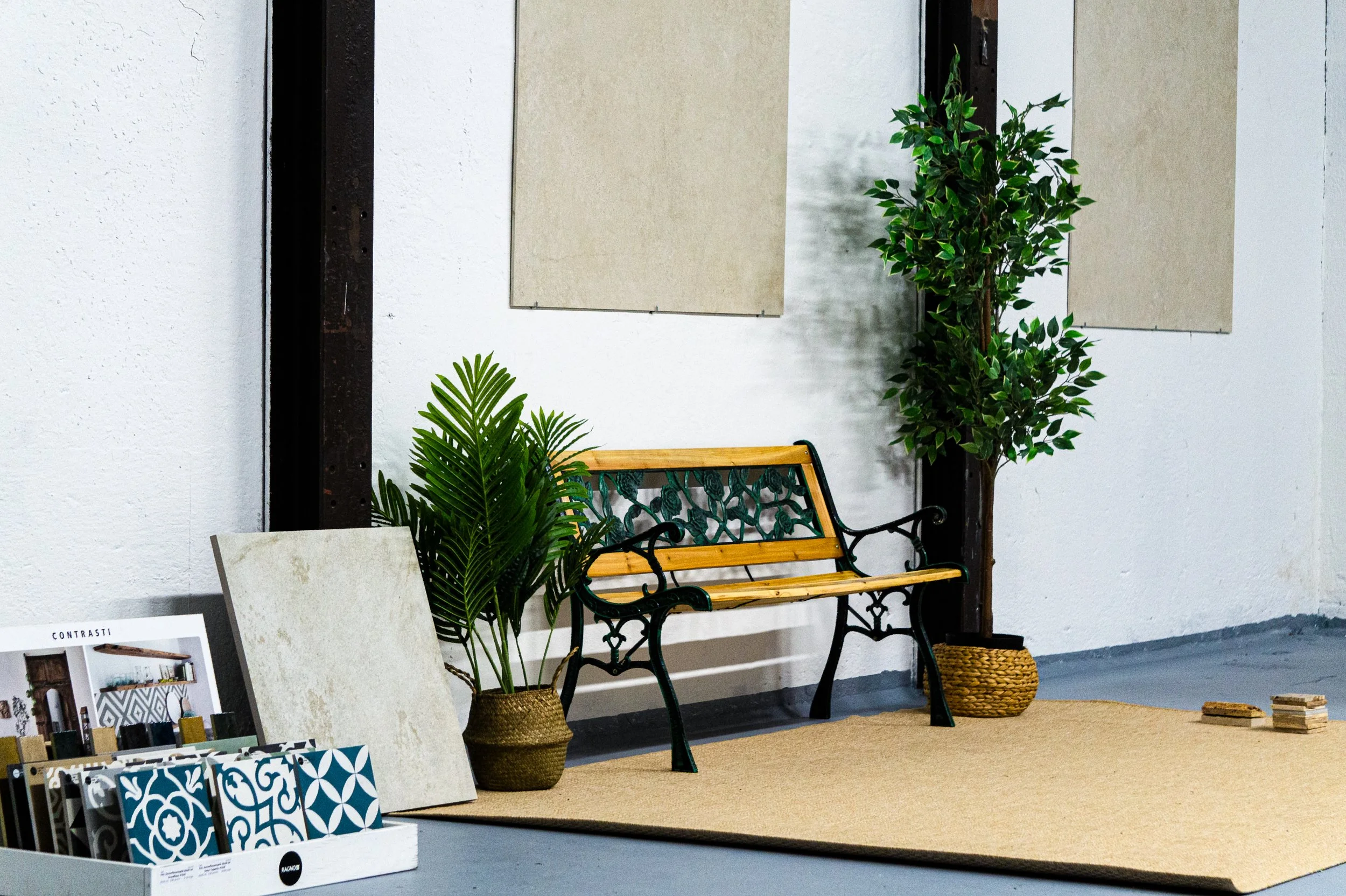 Eingangsbereich eines Warenhauses mit Sitzbank, Pflanzen und Musterstichproben im Vordergrund, an der Wand hängen Probenblätter. Aufgenommen von Hilal Studios.