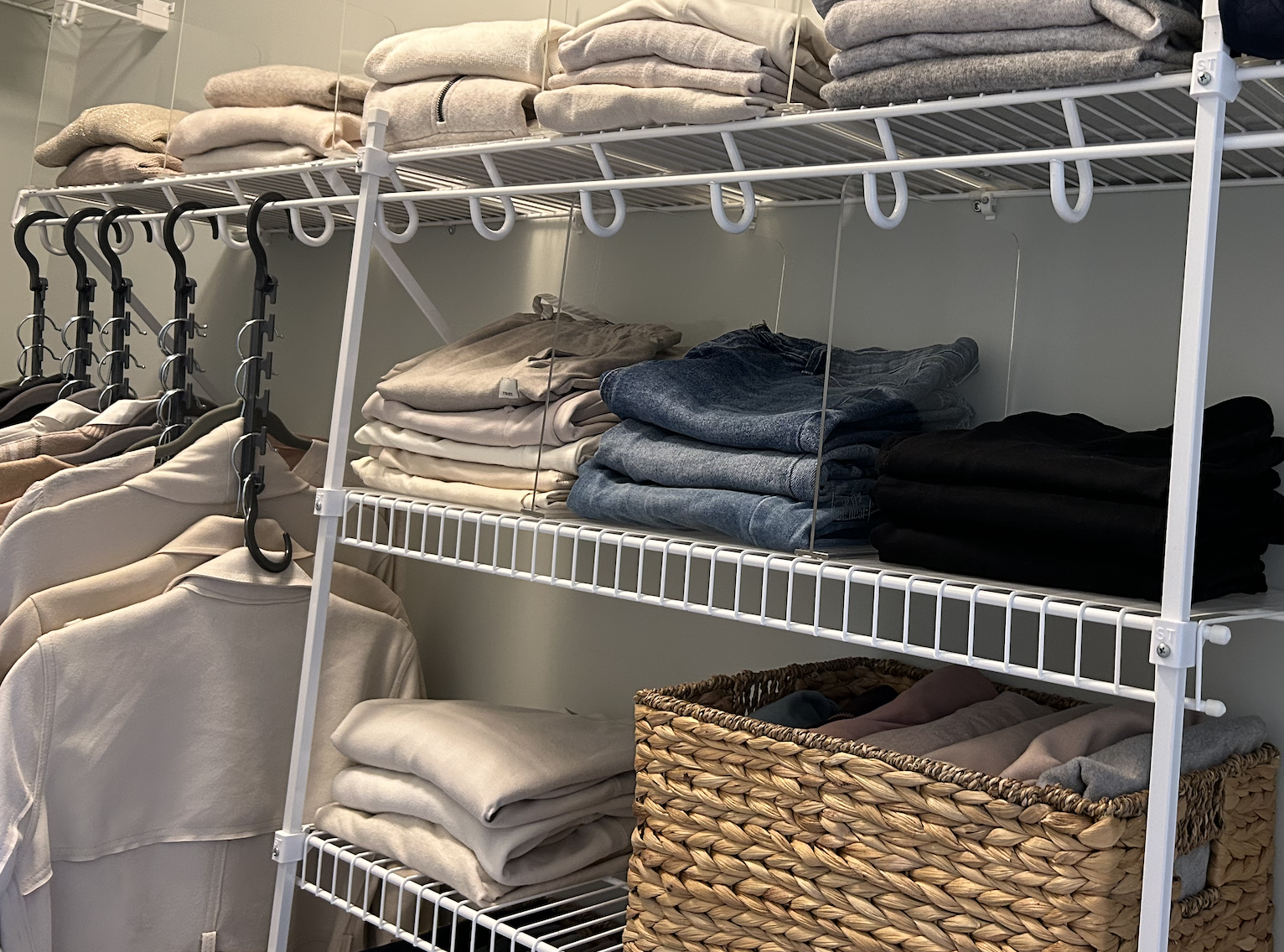 folded clothing and clothing on hangers in an organized closet with wire shelving