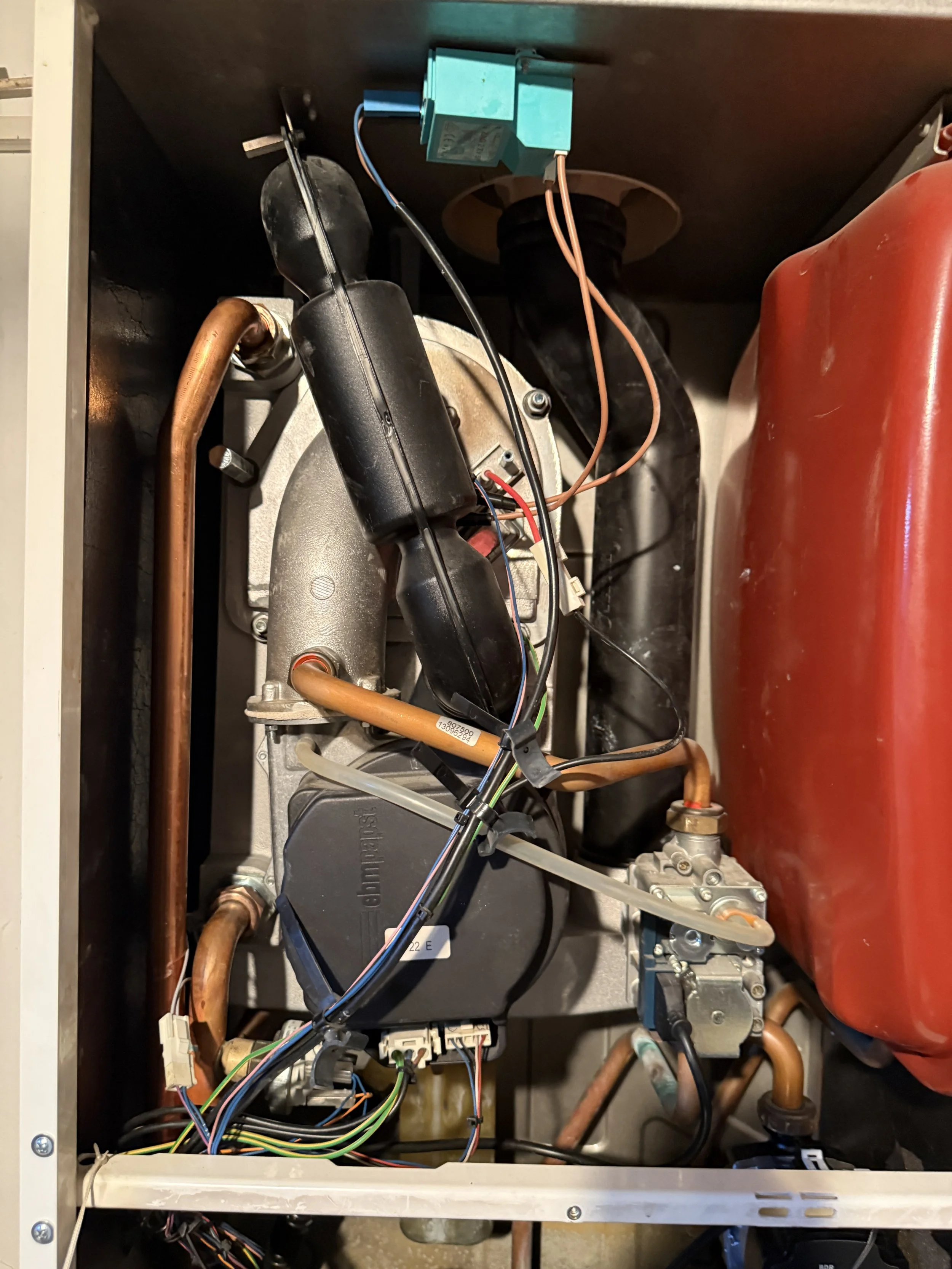 Innenseite eines technischen Geräts mit Komponenten, Drähten und Rohren.