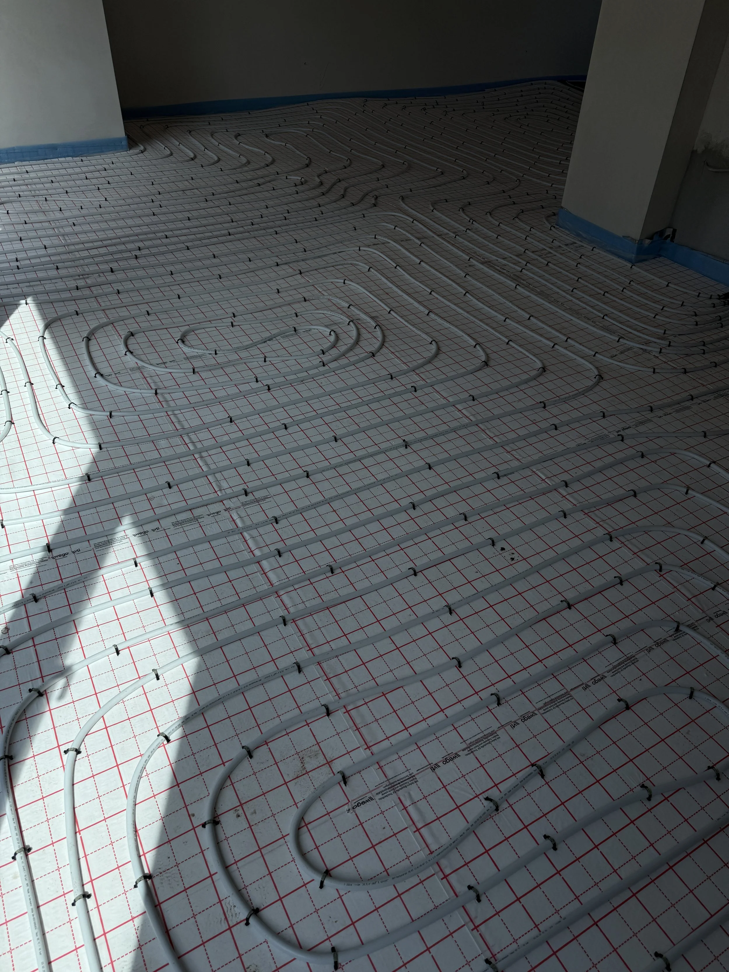 Installation einer Fußbodenheizung mit sichtbaren Heizrohren auf einem Unterboden.