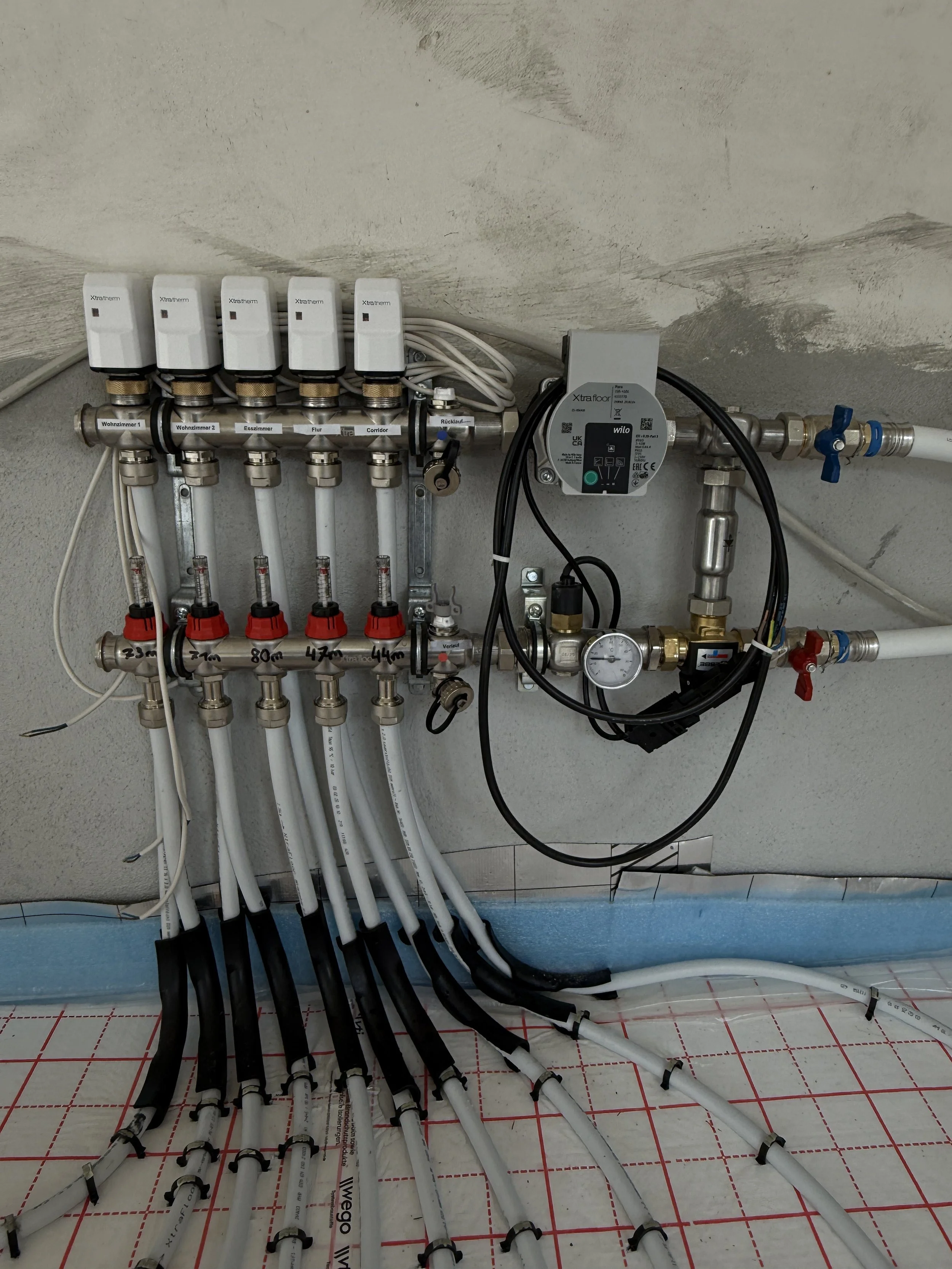 Installationsansicht eines Heizungs- oder Wasserverteilungssystems mit Rohren, Thermometern und Steuerungen.