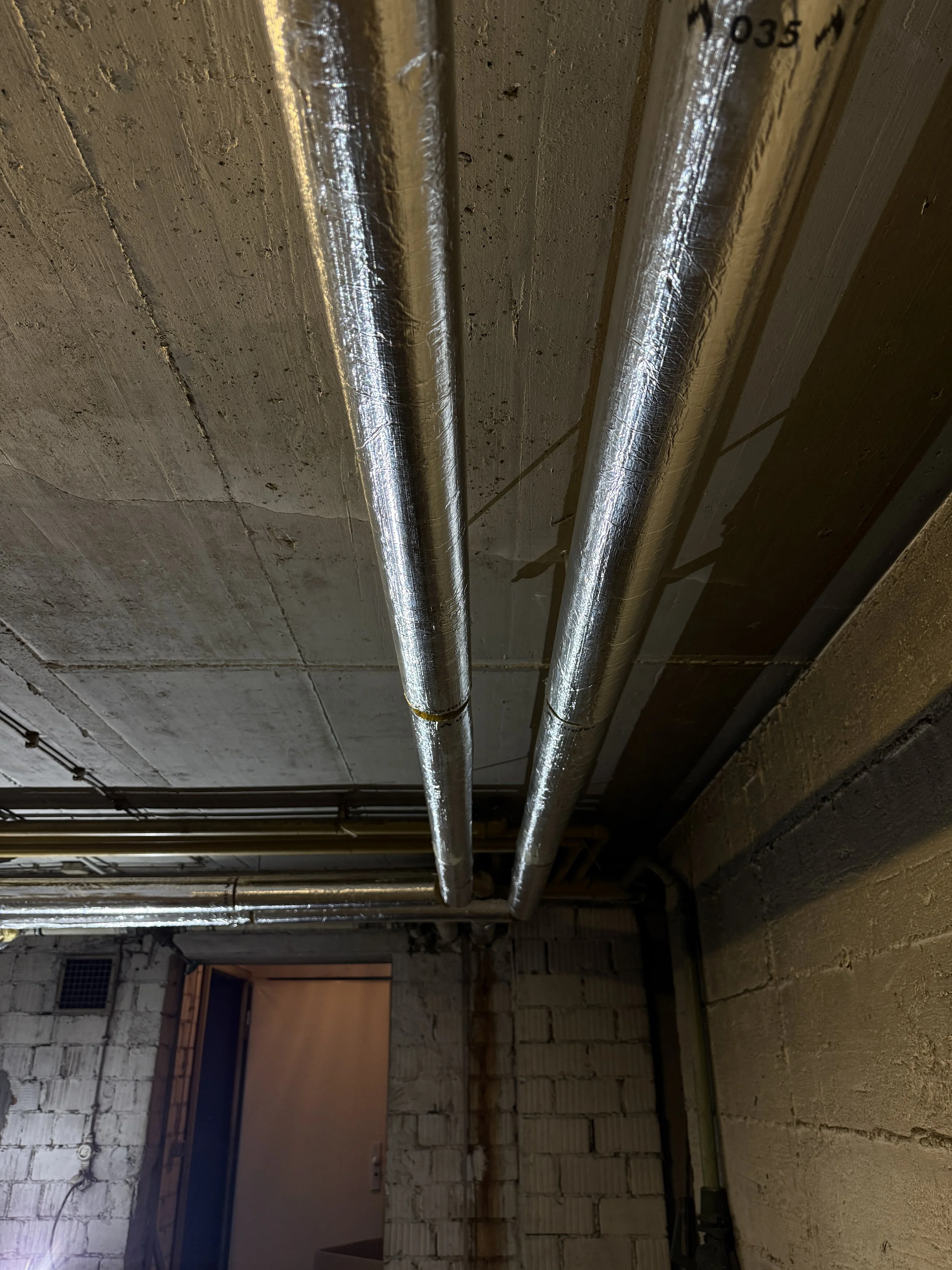 Doppelrohre aus Metall, installiert an einem Deckenabschnitt in einem Bauvorhaben. Die Rohre verlaufen parallel und sind Teil der Gebäudetechnik.