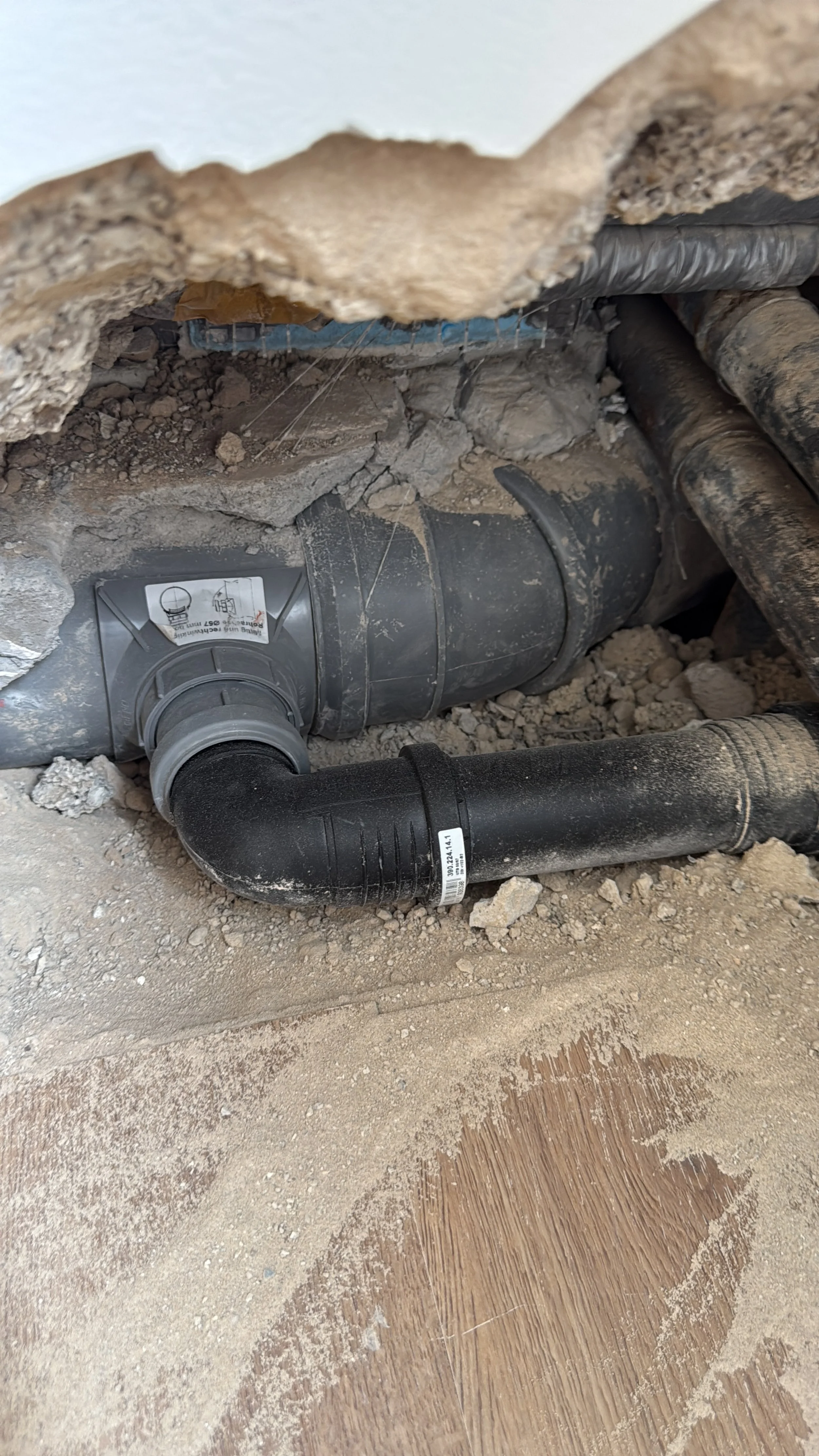 Installation von Abwasserrohren in einer Wand im Bauhaus, mit Schmutz und Erde um sie herum.