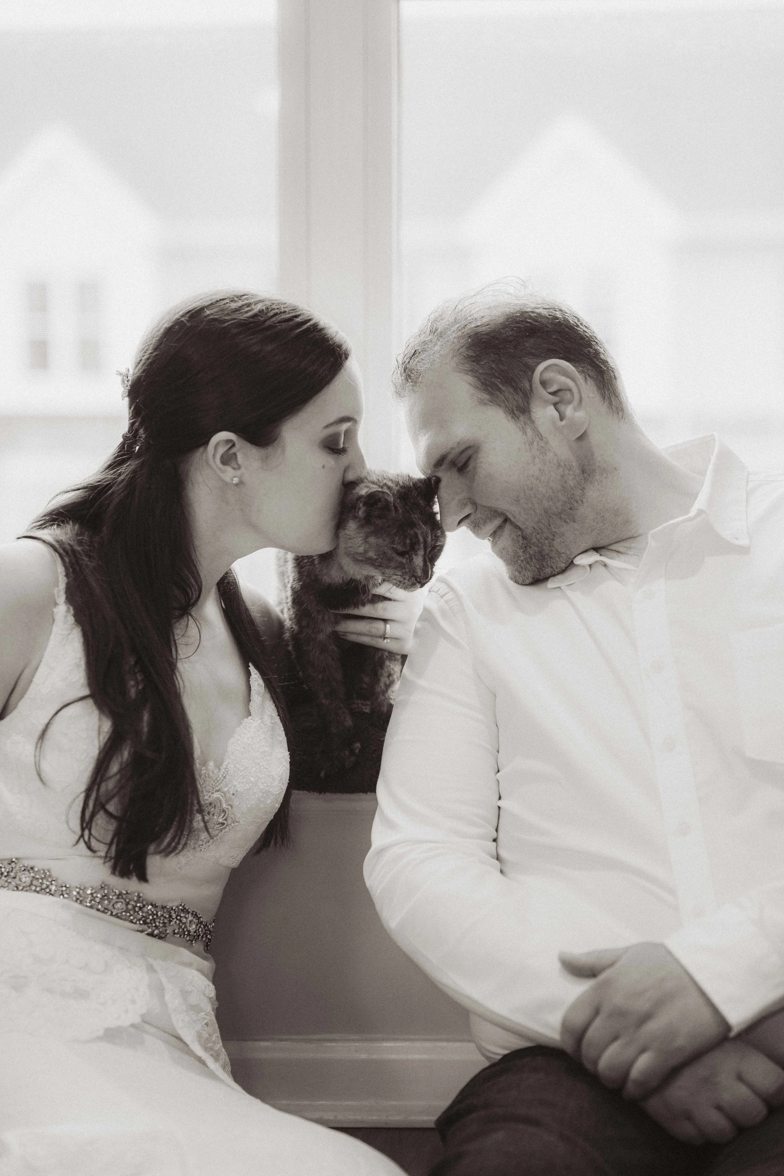 Close-up of a person wearing a black beanie, sunglasses, and black gloves, with red eye makeup and dangling earrings, in an urban setting.