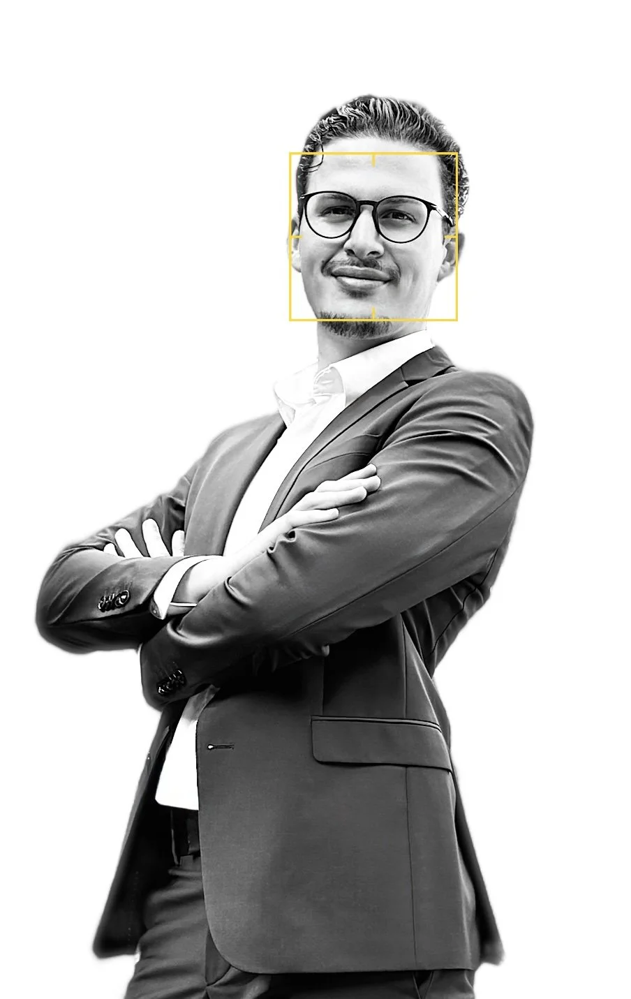 Schwarz-weiß-Bild eines selbstbewusst wirkenden Mannes, der eine Brille trägt, in einem Anzug und mit verschränkten Armen. Sein Gesicht ist im Fokus, mit einem leichten Lächeln.