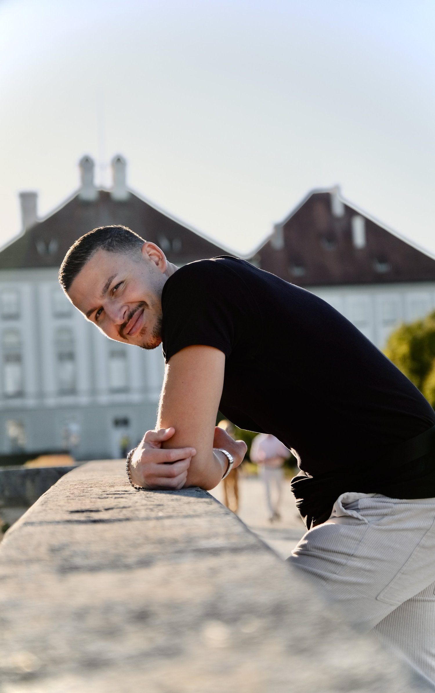 Dalyan Seyhan lehnt lächelnd an einer Mauer im Schlosspark Nymphenburg