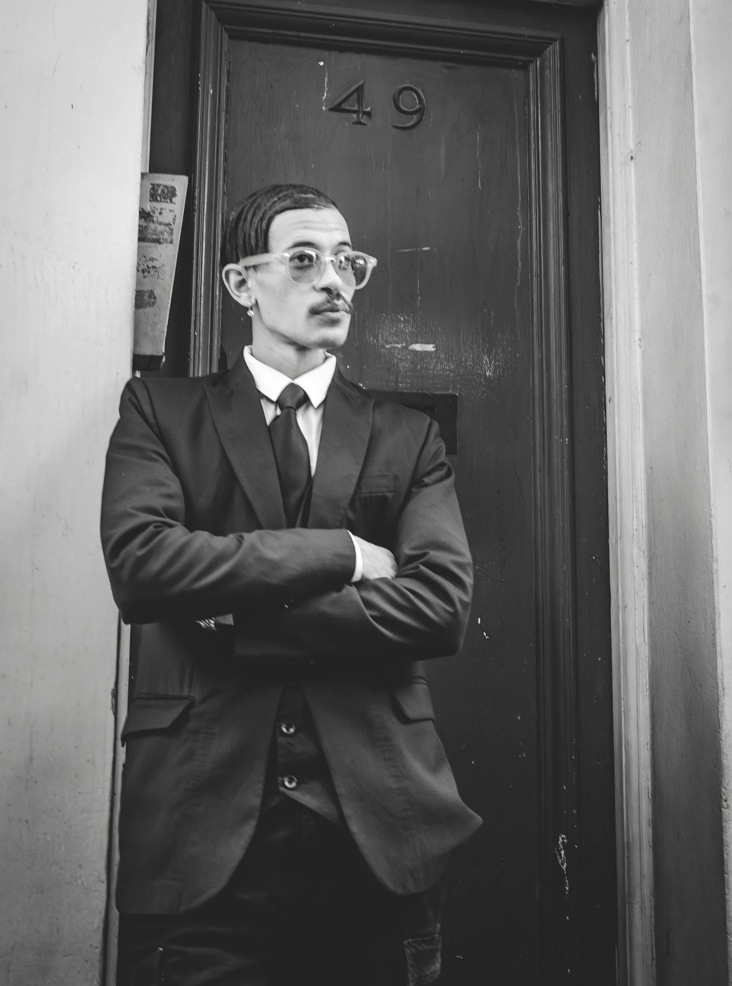 Not posed. Just there.
I saw him standing outside this doorway, arms crossed, sharp suit, perfect light and the scene framed itself. That&rsquo;s what I love about street photography: sometimes the city does all the work for you.

Would you have walk
