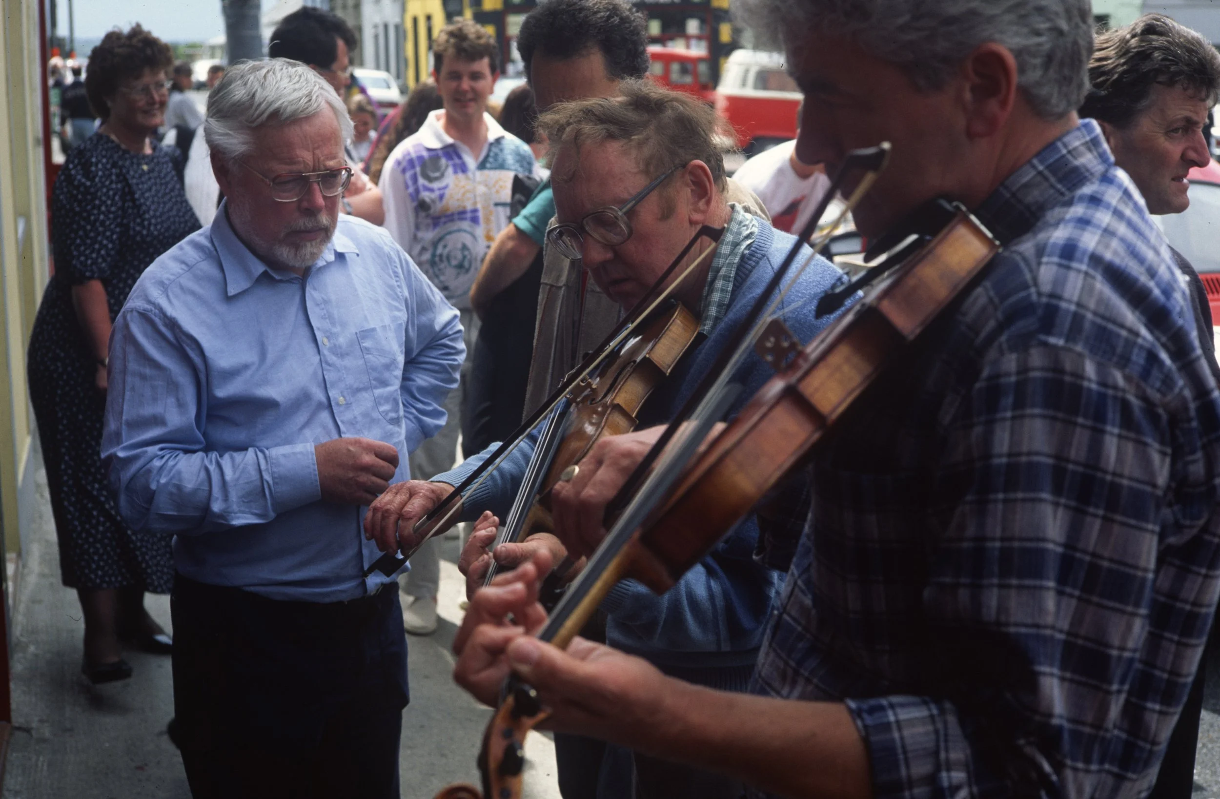 Peter Mackey watches John Joe Tuttle try out a fiddle for sale on Miltown Malbay's main street 1995.