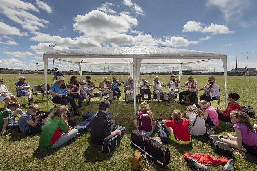 Master fiddle players playing for students at the GAA grounds.