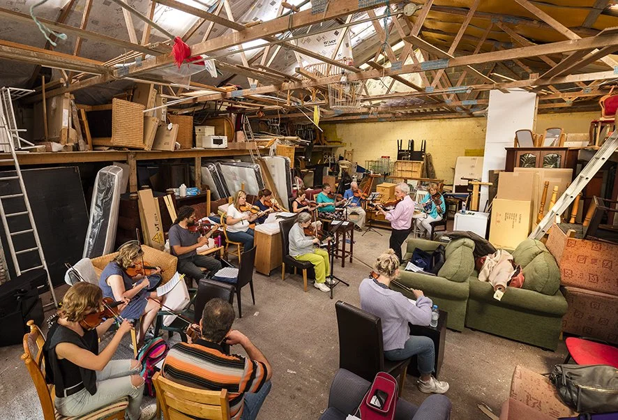 Vincent McMahon (standing) and his fiddle class in very unusual surroundings.