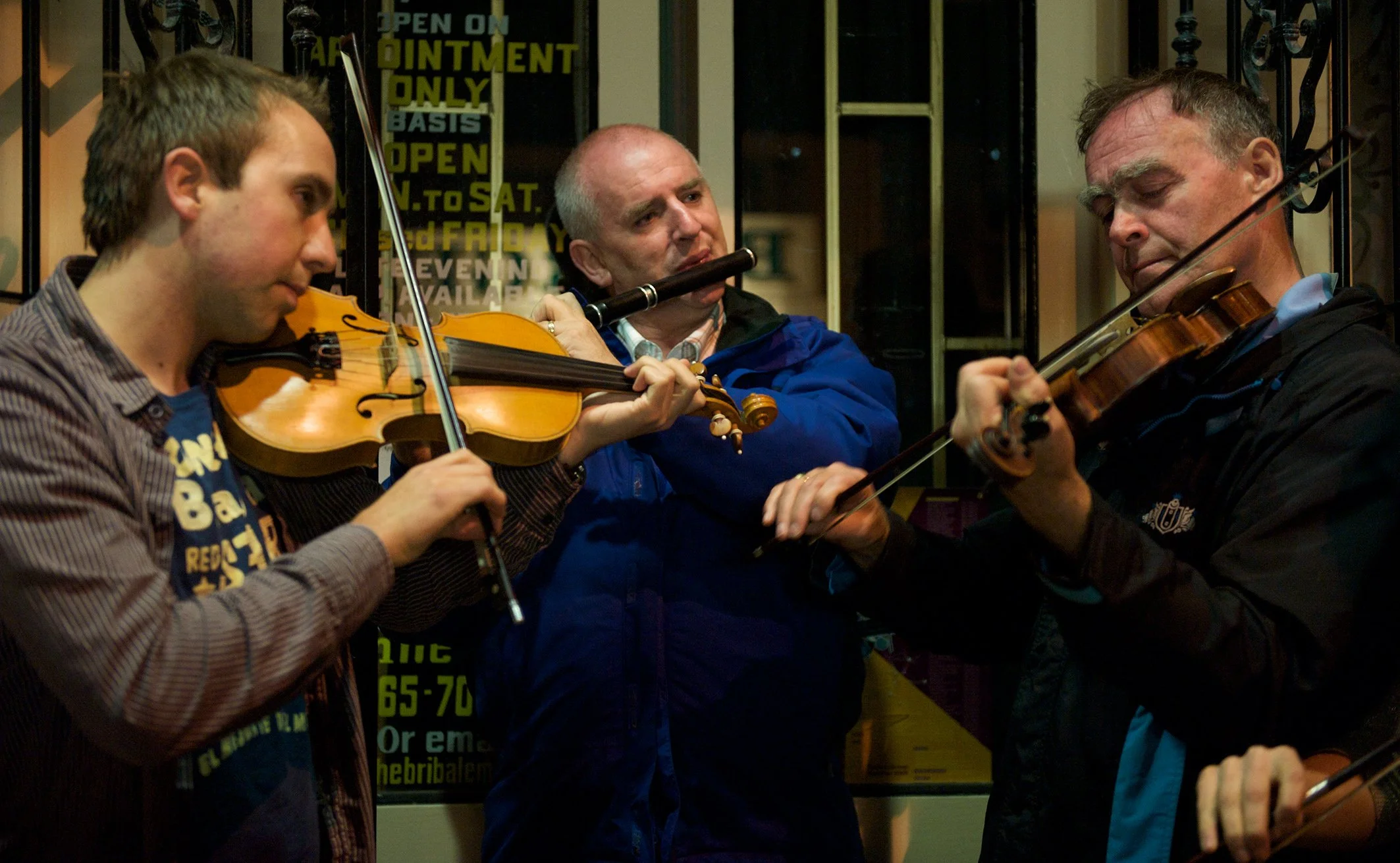 Oisín Mac Diarmada, Marcas Ó Murchú and Antóin Mac Gabhann playing in a session on Miltown Malbay's main street 2009.